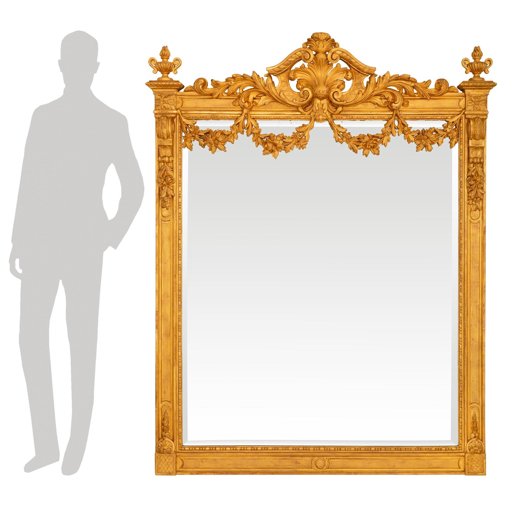 Un magnifico ed elegante specchio in legno dorato francese del XIX secolo Luigi XVI. L'originale piastra a specchio smussata è incorniciata da una fascia decorativa con perline. La cornice presenta una riserva centrale circolare in basso e rosette a