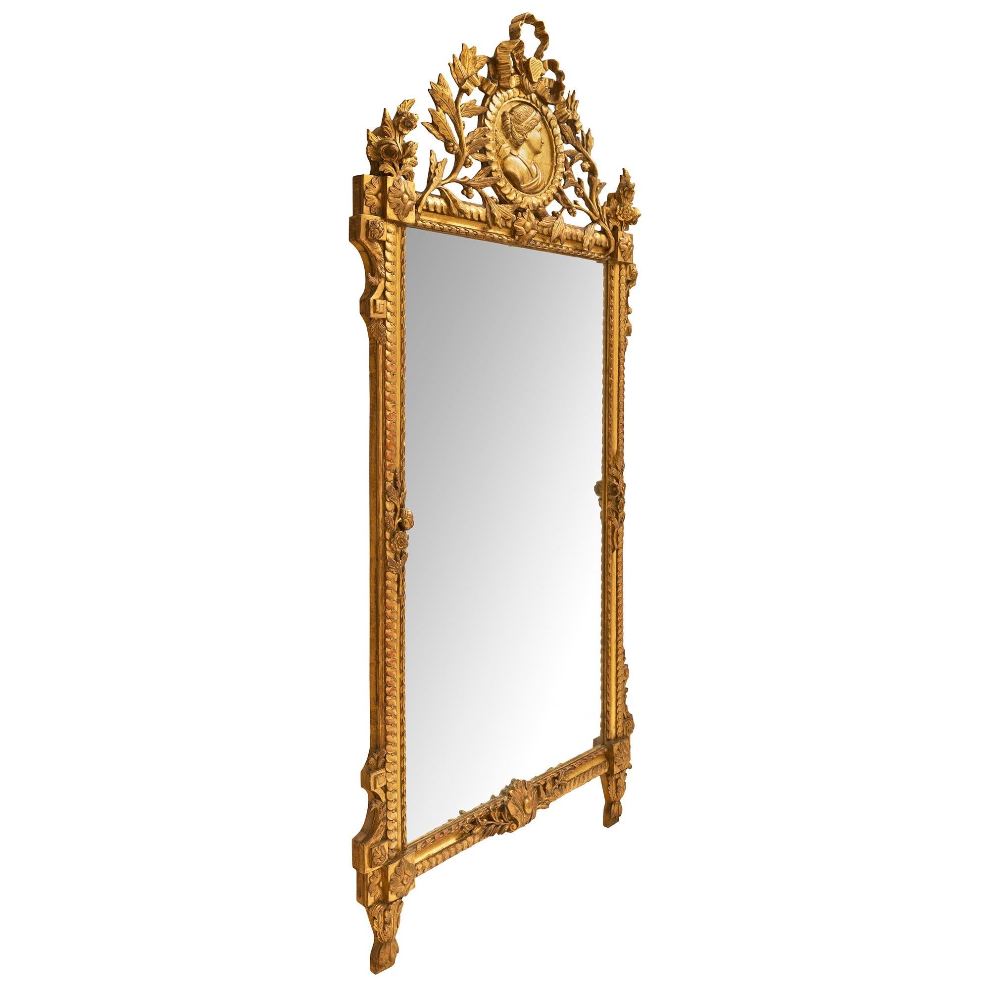A sensational and large scale French 19th century Louis XVI st. Giltwood mirror with all original gilt and richly carved throughout. The frame with an intertwined ribbon design and twisted rope has large acanthus leaves at the bottom below rosettes.