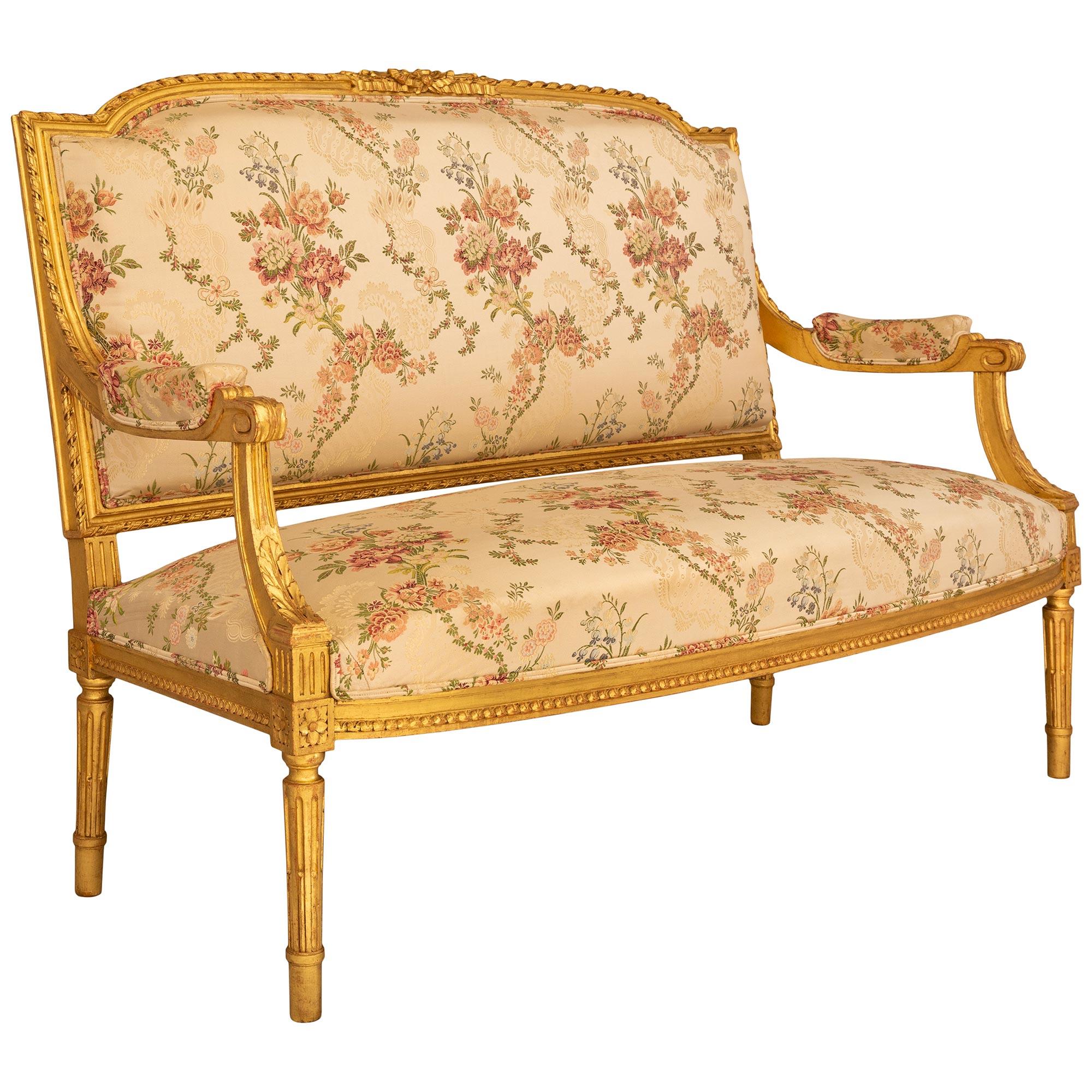 Canapé décoratif et très élégant en bois doré de style Louis XVI du XIXe siècle. Ce magnifique canapé repose sur quatre pieds droits fuselés et cannelés, avec des blocs de couronnement du plateau finement sculptés d'une rosette. Les blocs de