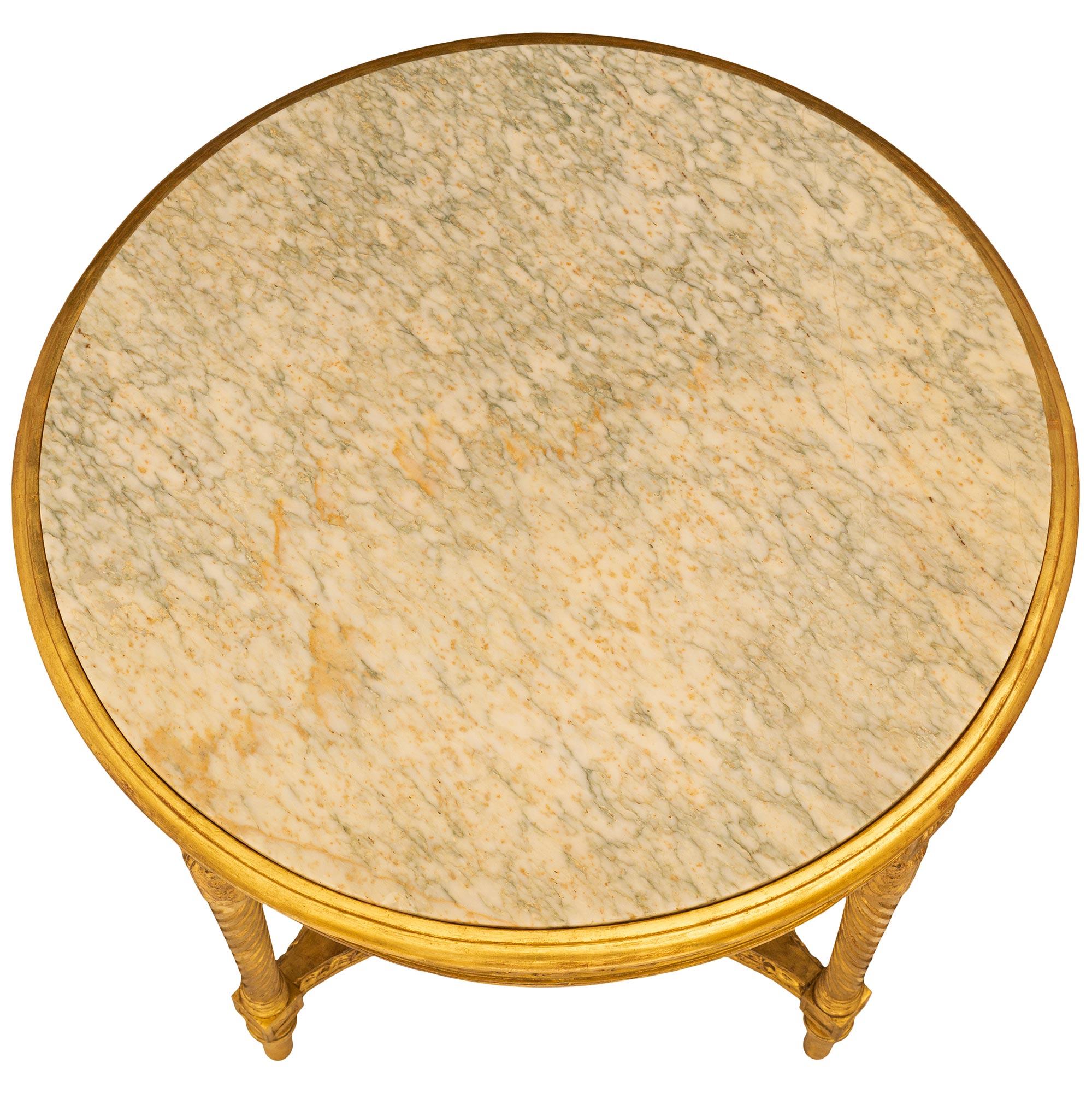An exquisitely decorated French 19th century Louis XVI st. Giltwood side table. This elegant and highly detailed circular table is supported by four tapered circular feet with a top band. The four legs are joined by a bottom stretcher with a woven
