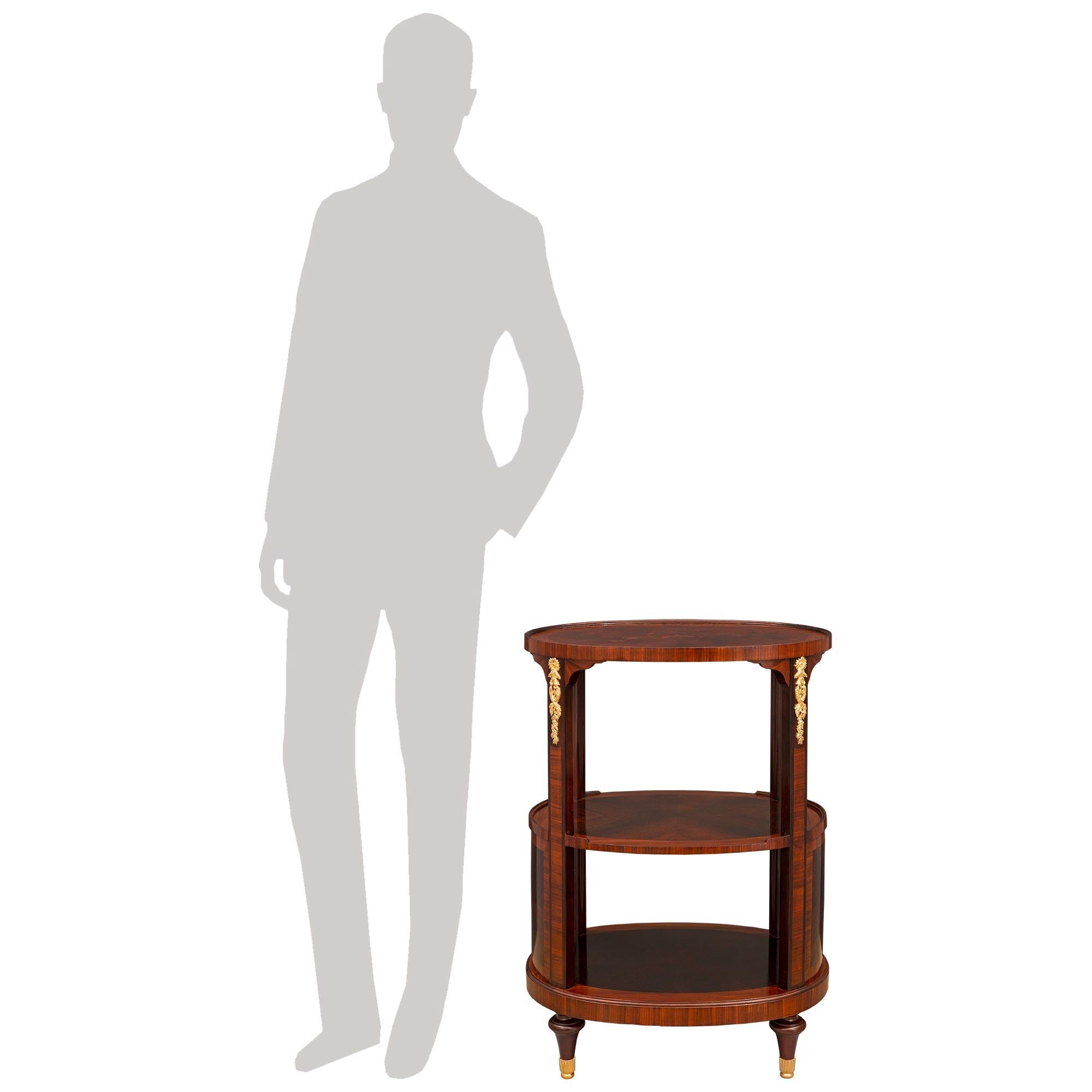 Charmante table d'appoint en bois de roi et bronze doré de style Louis XVI du XIXe siècle, attribuée à Durand. La table de forme oblongue à trois niveaux repose sur d'élégants pieds fuselés en forme de topie avec de jolis sabots feuillagés en bronze