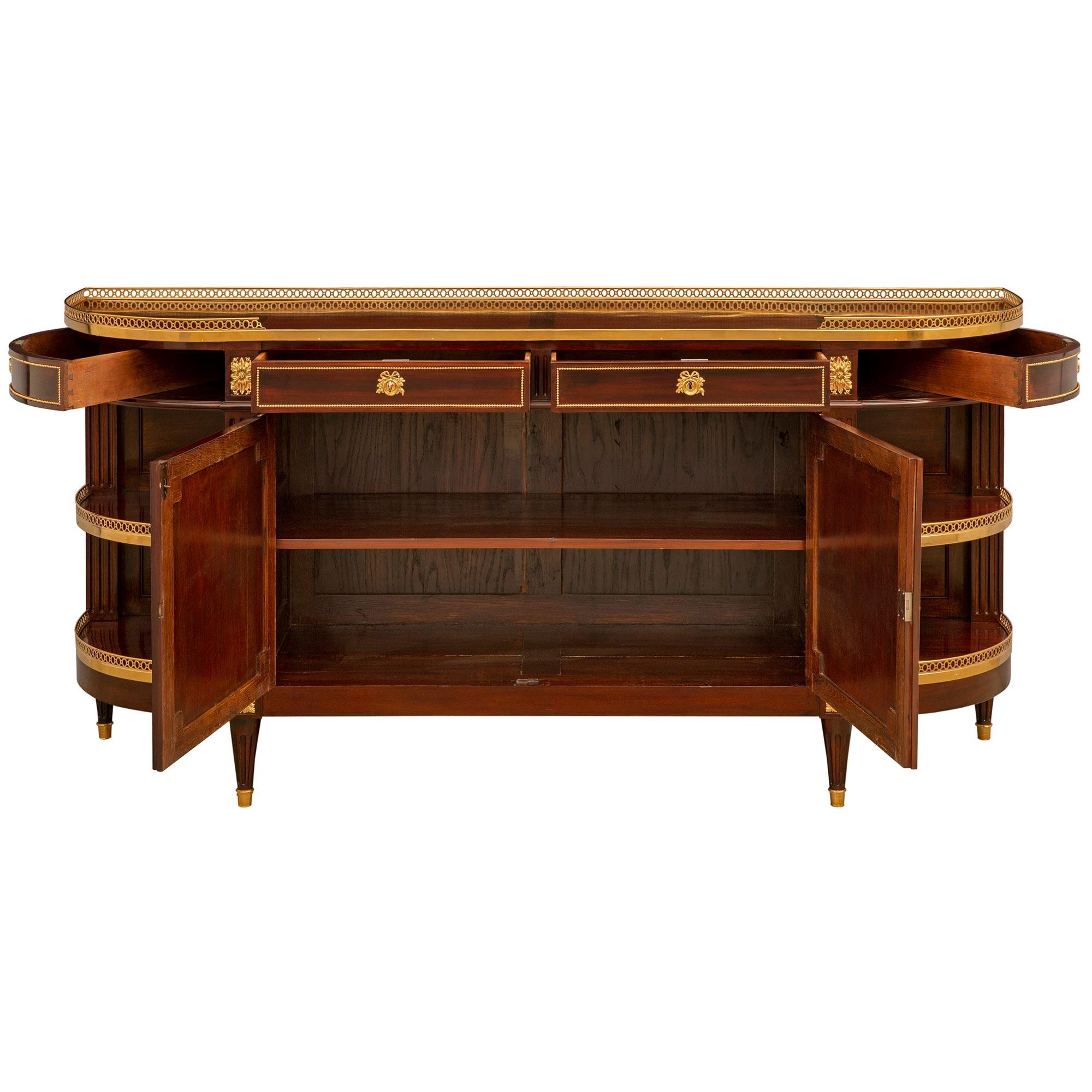 An exceptional and most elegant French 19th century Louis XVI st. Mahogany and Ormolu buffet. The buffet is raised on lovely circular tapered fluted legs with fine mottled Ormolu sabots and below rosettes flanking the Mahogany frieze. Above the