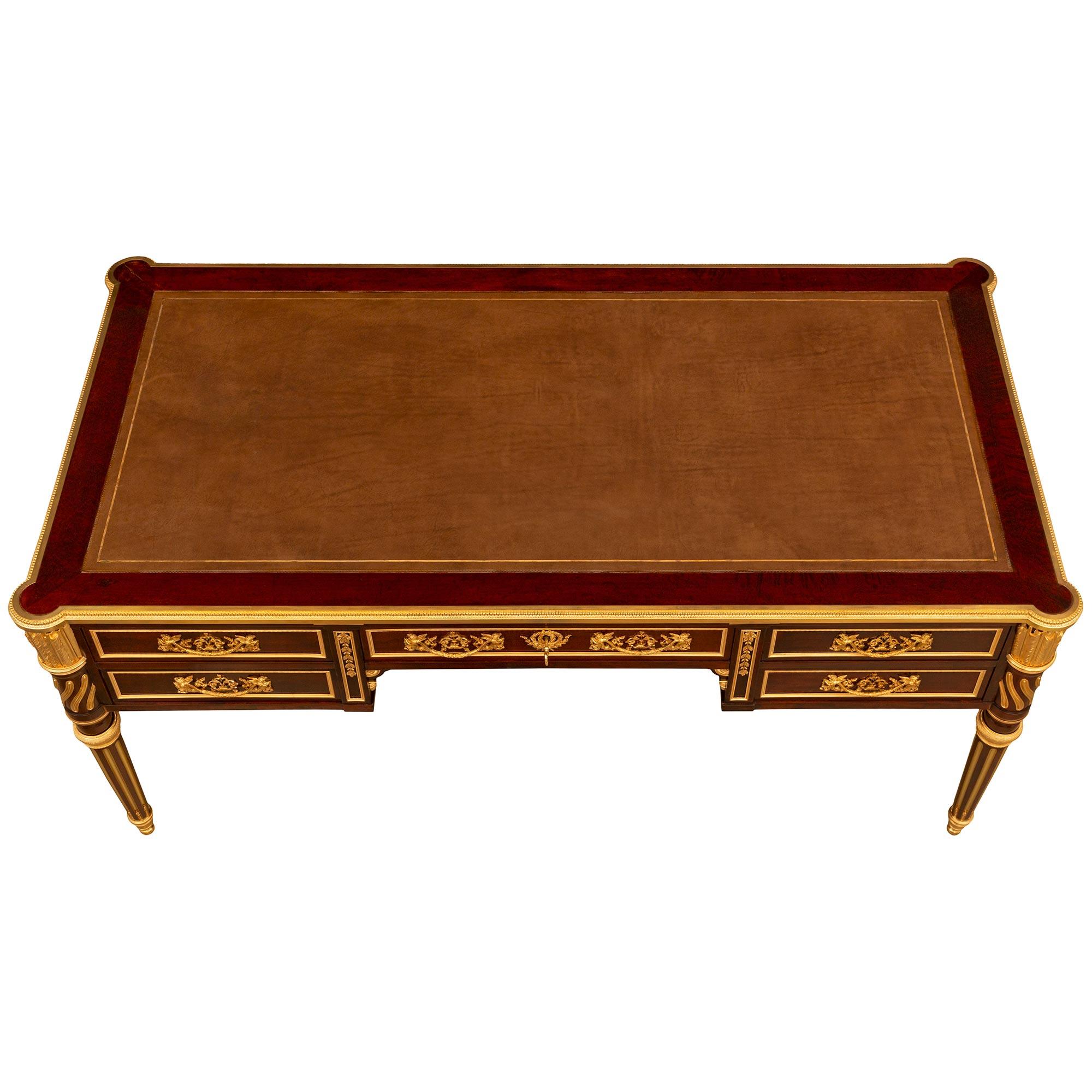 An impressive and high quality French 19th century Louis XVI st. mahogany and ormolu mounted partners desk signed by Victor Raulin. The desk is raised by circular tapered fluted legs ending with topie shaped ormolu sabots. The flutes are elegantly