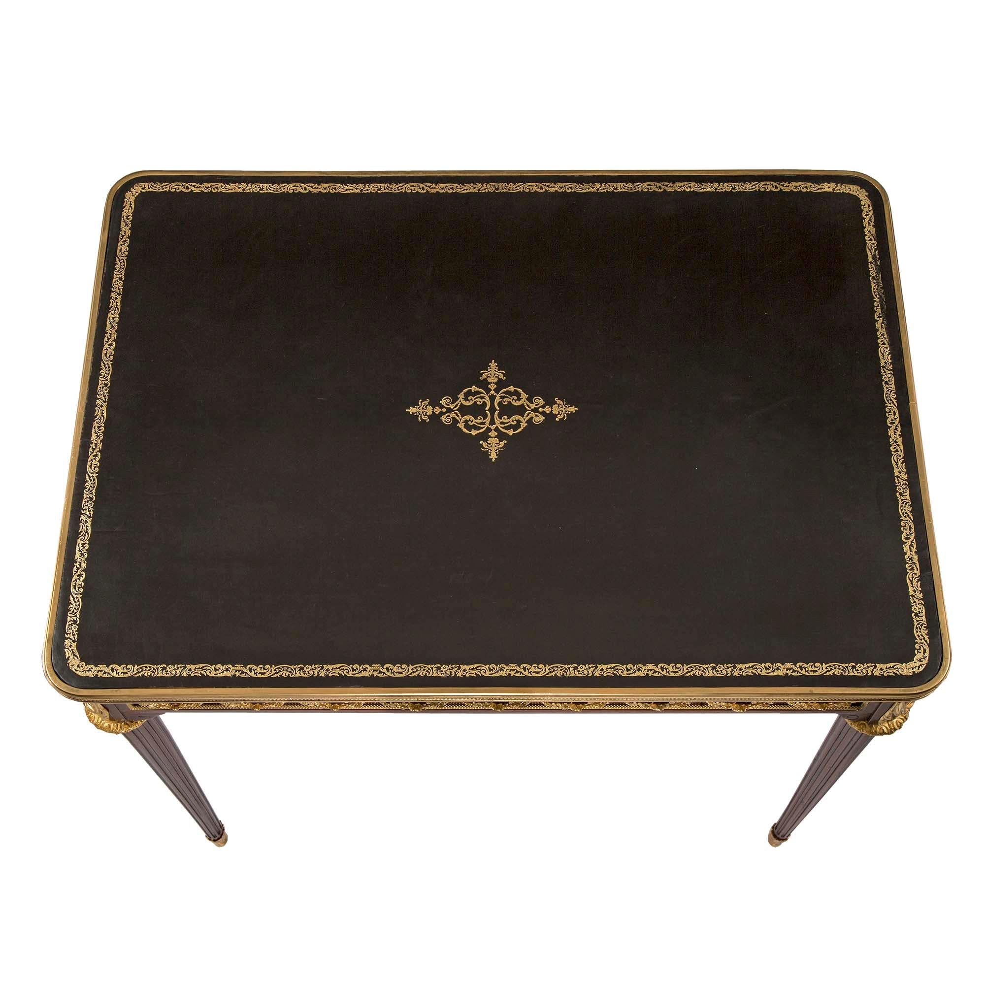 A most elegant French 19th century Louis XVI St. mahogany and ormolu writing desk, attributed to F. Linke. The lovely desk is raised by circular tapered fluted legs with fine foliate wraparound ormolu sabots and rich decorative ormolu top caps, in a