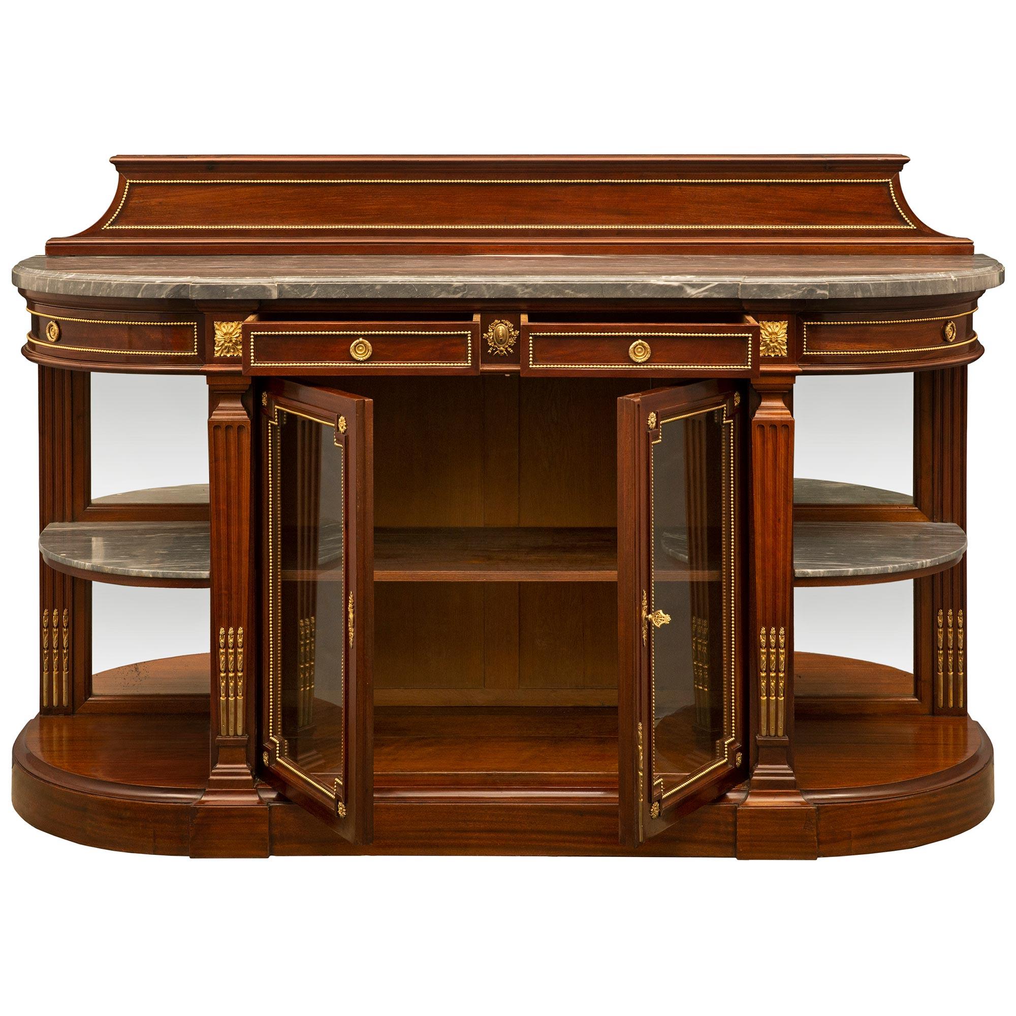 A superb and high quality French mid 19th century Louis XVI st. mahogany buffet. The buffet is raised on a demi lune base with four tapered reeded columns with ormolu chandelles supporting the frieze. Two central mahogany doors with the original
