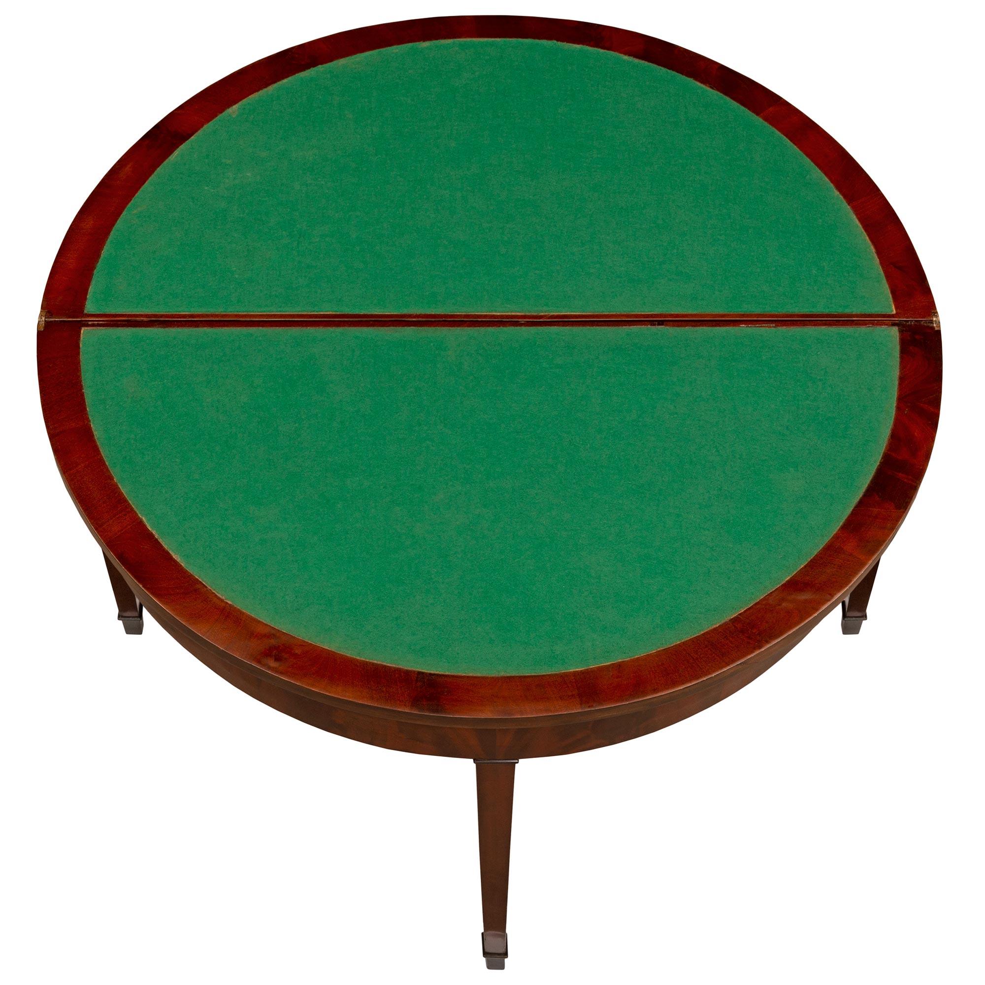 Une élégante console/table de jeux française du 19ème siècle en acajou de style Louis XVI. La table est surélevée par quatre pieds fuselés carrés avec des sabots et des chapeaux supérieurs finement marbrés. Le tablier droit et le plateau poli à la