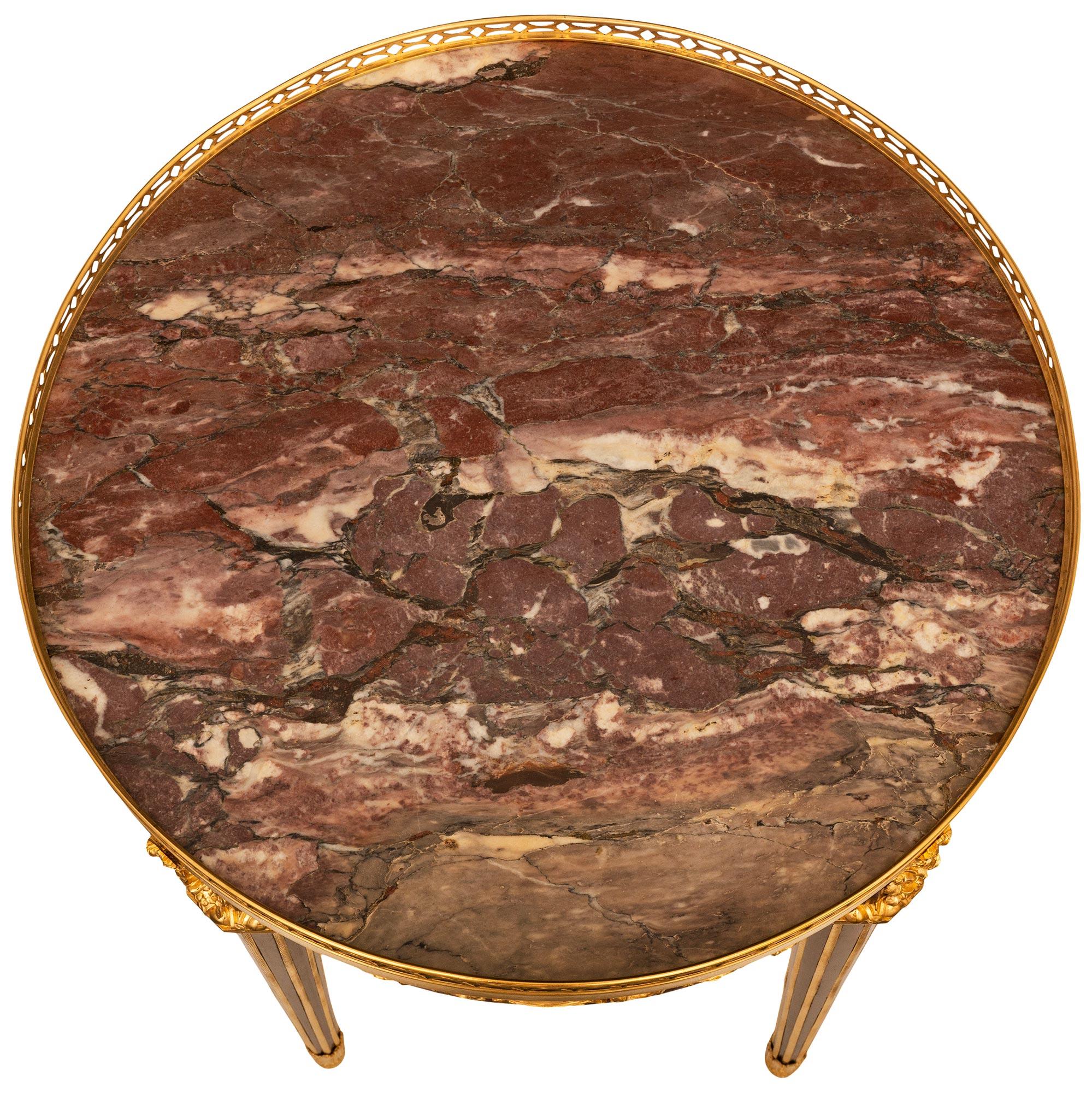 A stunning and highly quality French 19th century Louis XVI st. Mahogany, Satinwood, Ormolu, and Breccia Violette Marble side table, attr. to Theodore Millet. This exquisite single drawer circular side table is raised by four octagonal tapered