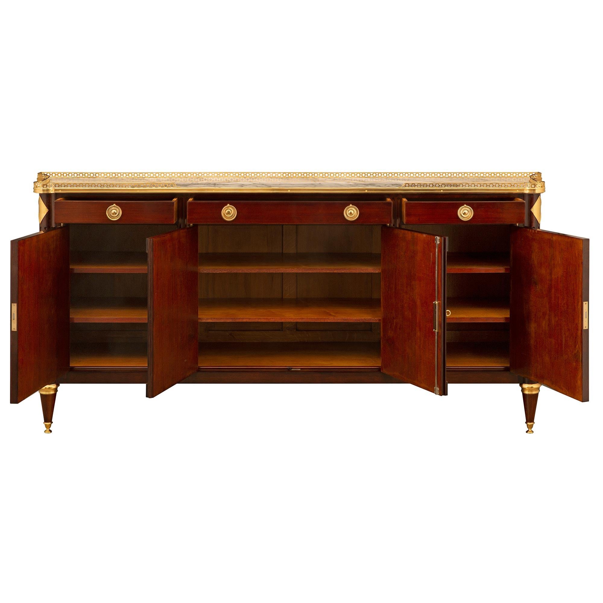 A stunning and extremely elegant French 19th century Louis XVI st. Mahogany, ormolu, and Arabescato marble buffet. The four door three drawer buffet is raised by beautiful topie shaped tapered legs with fine ormolu feet and wrap around mottled top