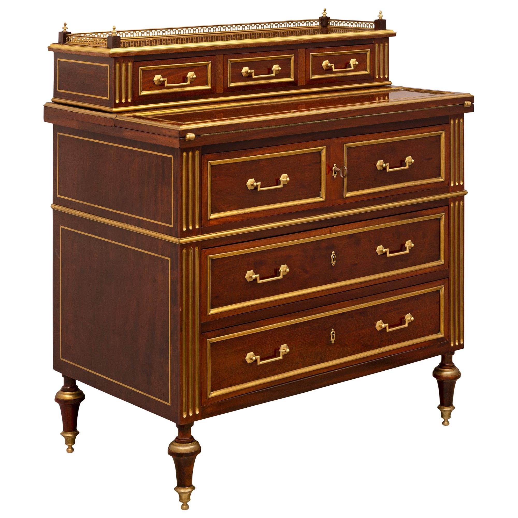 An elegant and high quality French 19th century Louis XVI st. Mahogany, ormolu, and brass desk. The six drawer Bonheur du Jour desk is raised by most decorative slender topie shaped legs with delicately fitted ball sabots below striking fluted