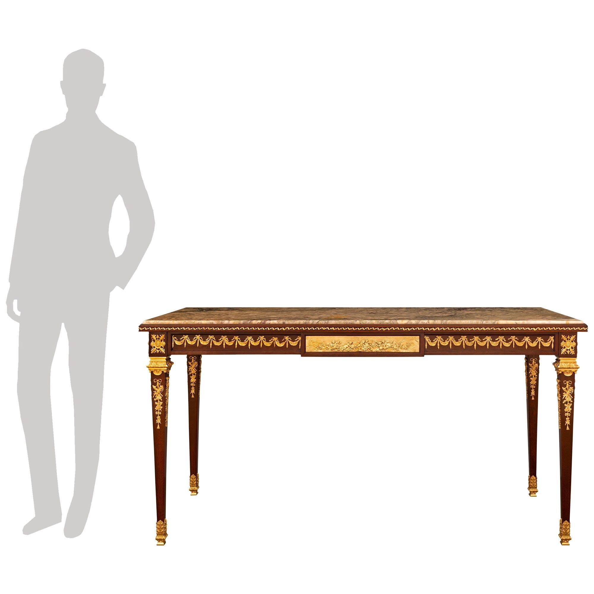 Mesa/escritorio central de caoba, ormolu y mármol Breccia Aurora, de gran calidad y elegancia, atribuida a François Linke. Este impresionante centro de mesa se eleva sobre elegantes patas cónicas cuadradas con hermosos sabots foliados de Ormolu,