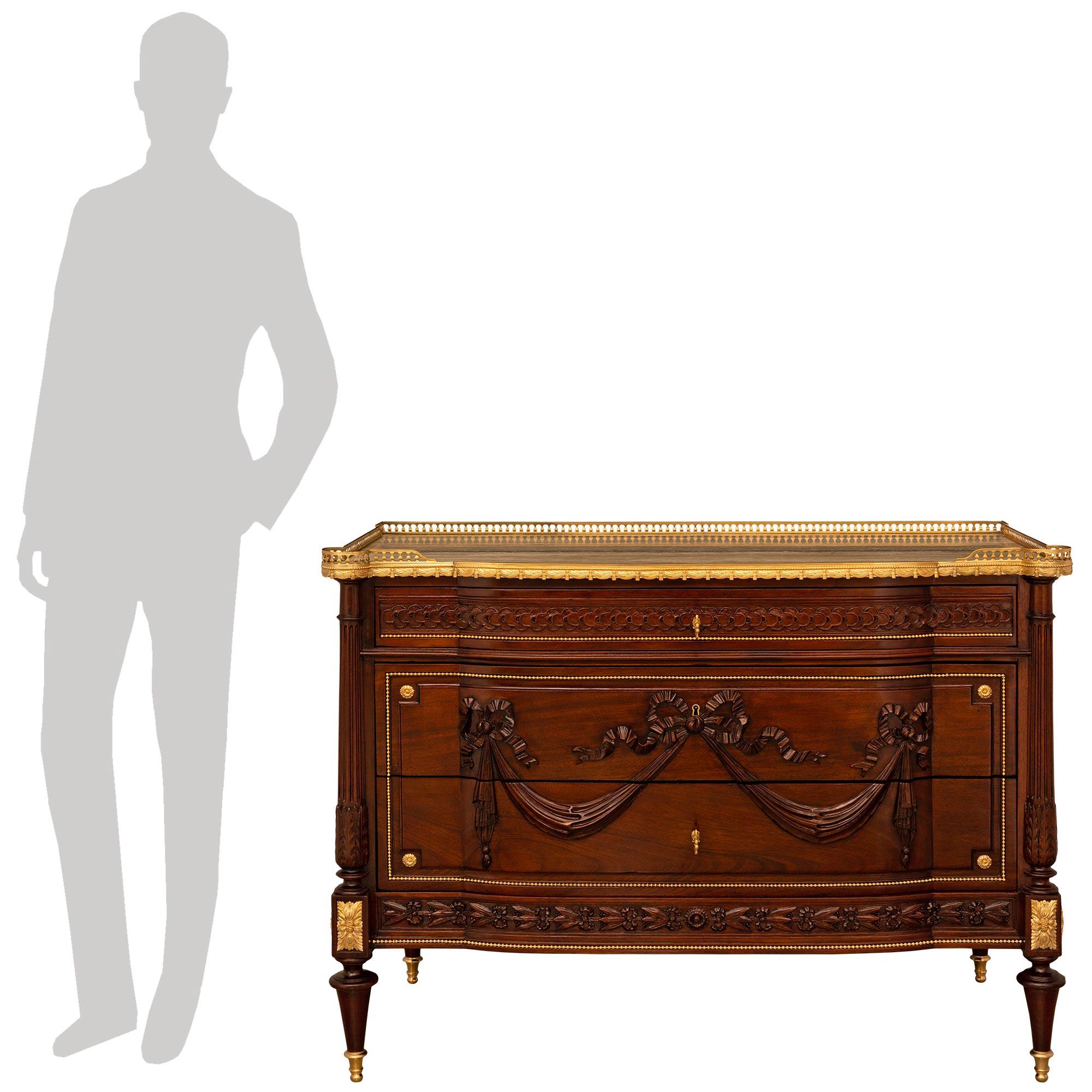 A stunning and high quality French 19th century Louis XVI st. Mahogany, Ormolu, and Stone commode. This highly detailed three drawer commode is raised on four Mahogany legs supported on Ormolu topie shaped sabots. The straight front apron is