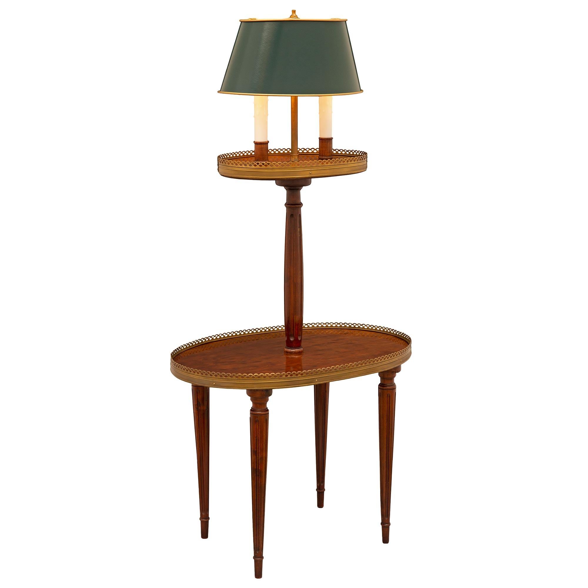 A charming French 19th century Louis XVI st. Mahogany, ormolu, and tole side table. The two tier table and lamp are raised by most elegant circular tapered fluted legs with fine mottled top caps. The bottom tier displays a lovely French polished top