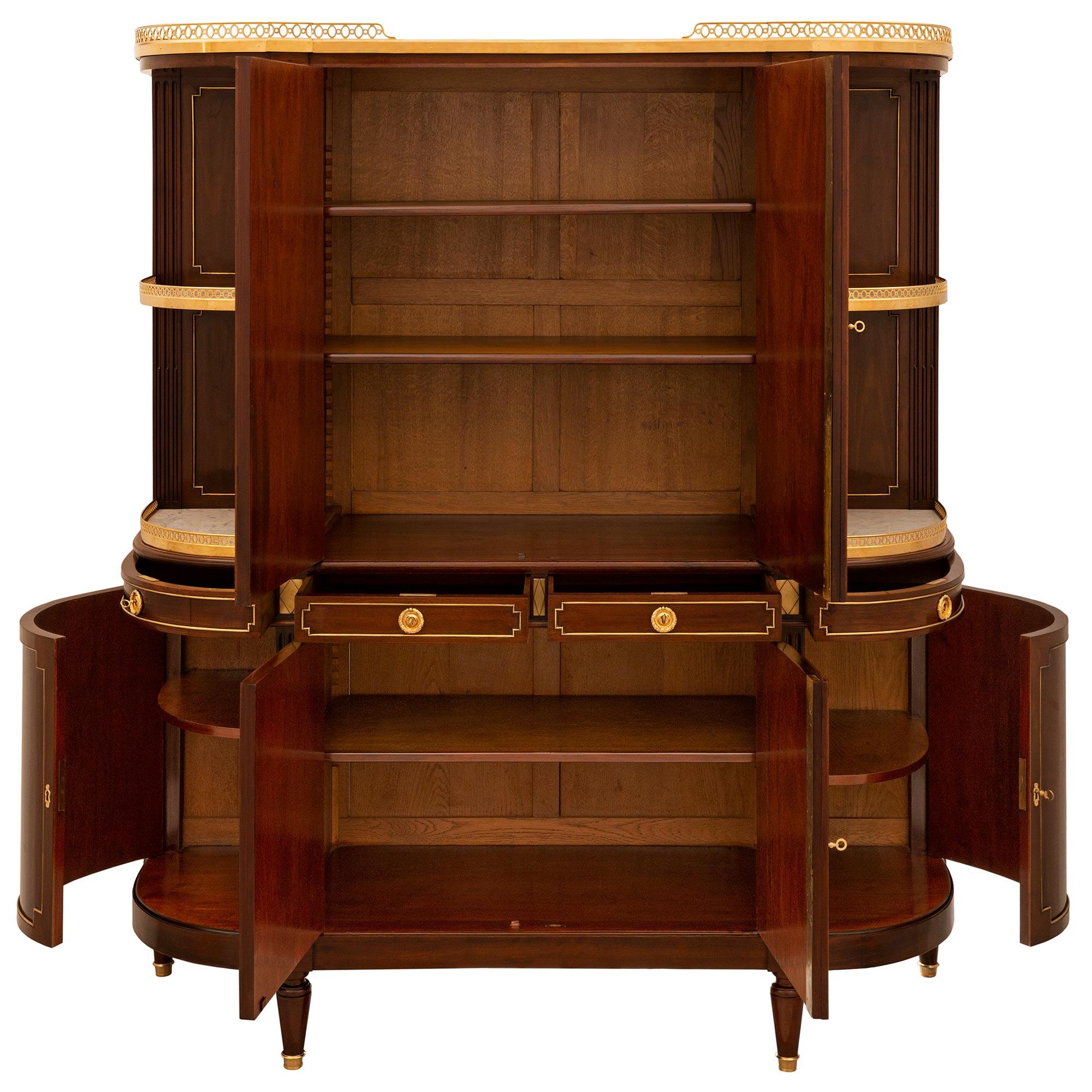 An extremely elegant and high quality French mid-19th century Louis XVI st. mahogany, brass and ormolu mounted Deux-Corps cabinet. The cabinet is raised by topie shaped legs below two curved solid mahogany doors and two central doors. The doors are