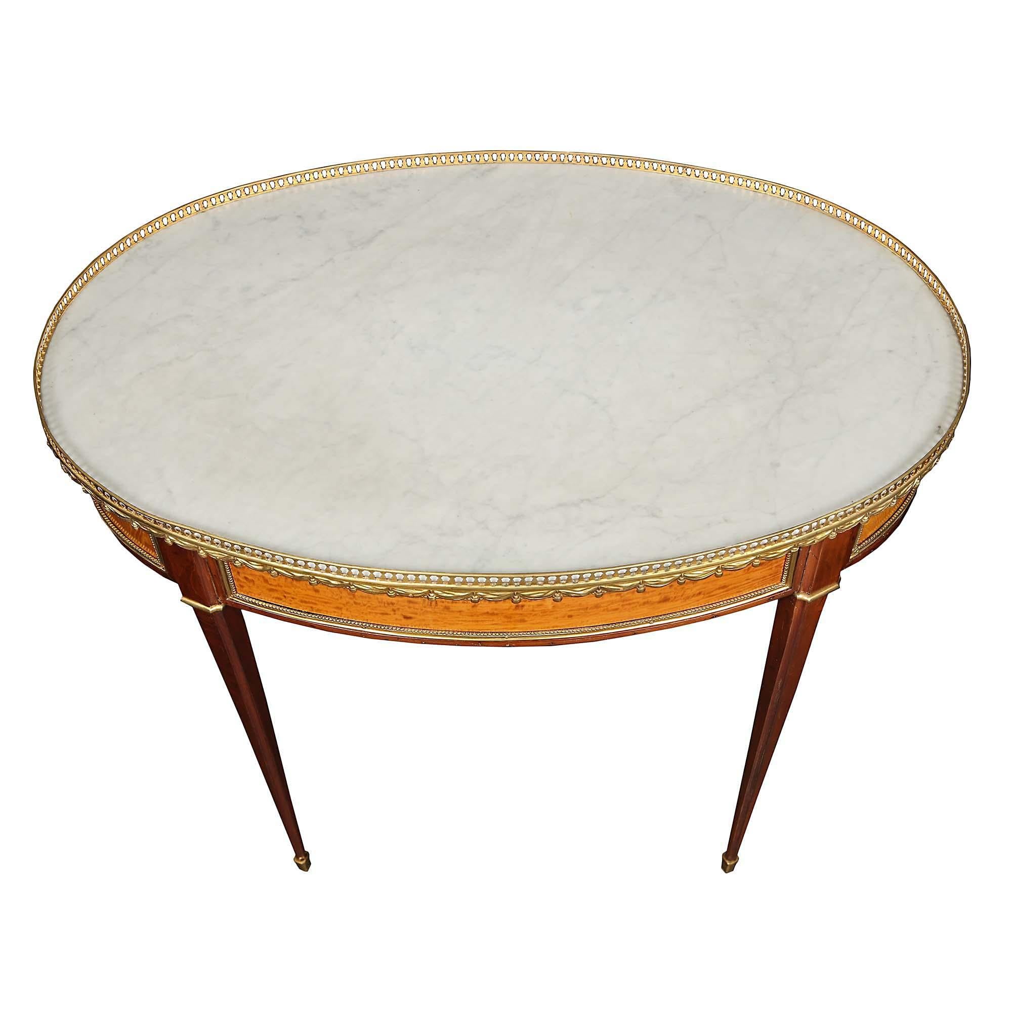 A very elegant French mid 19th century Louis XVI st. mahogany and satinwood oval side table. The table is raised by tapered legs with ormolu sabots and top bands. The satinwood paneled frieze is bordered by a beaded ormolu trim. All below a white