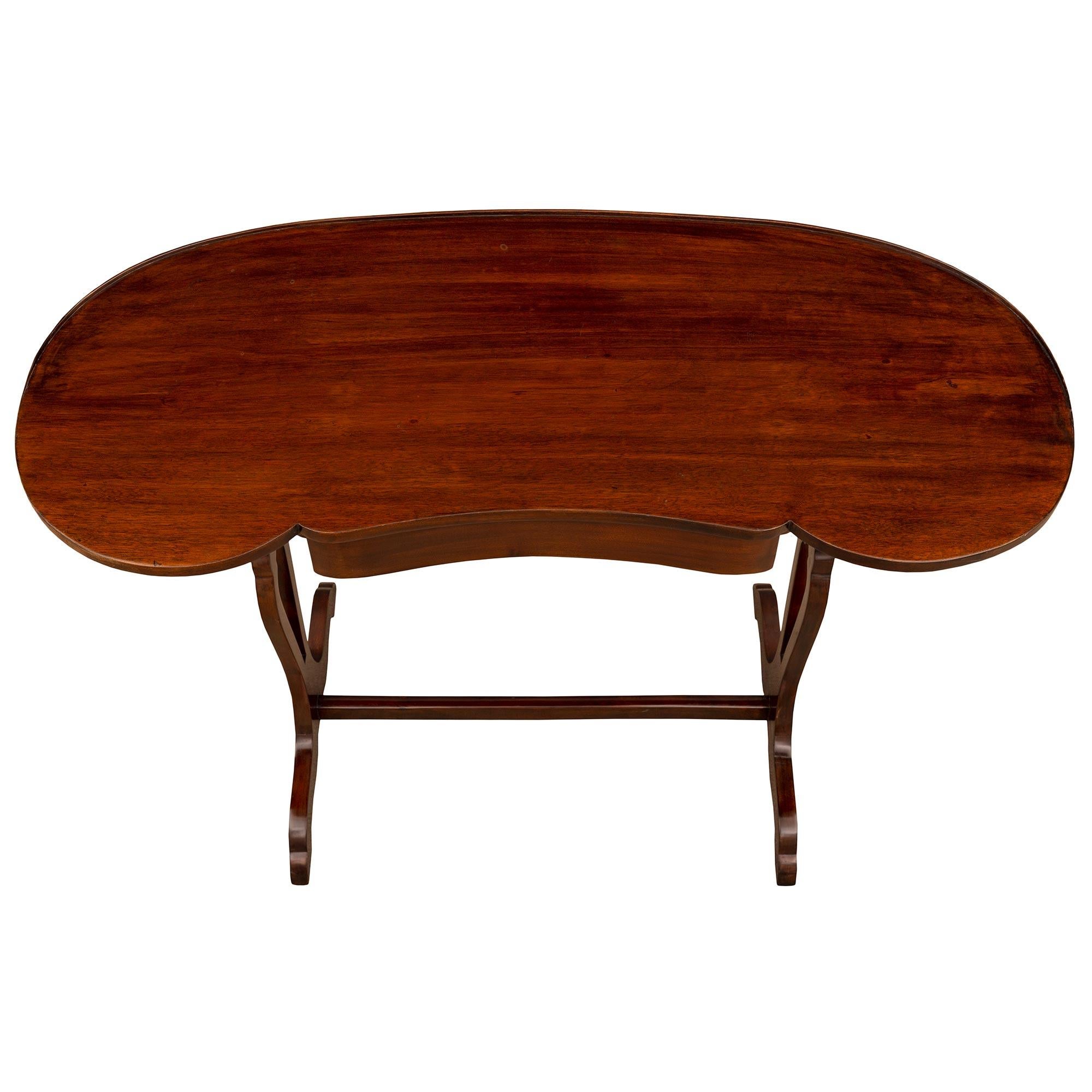 A lovely French 19th century Louis XVI st. Mahogany side table/desk. The kidney shaped Table à Écrire is raised by elegantly curved supports connected with a fine stretcher below the beautiful pierced baluster shaped supports. The top displays a