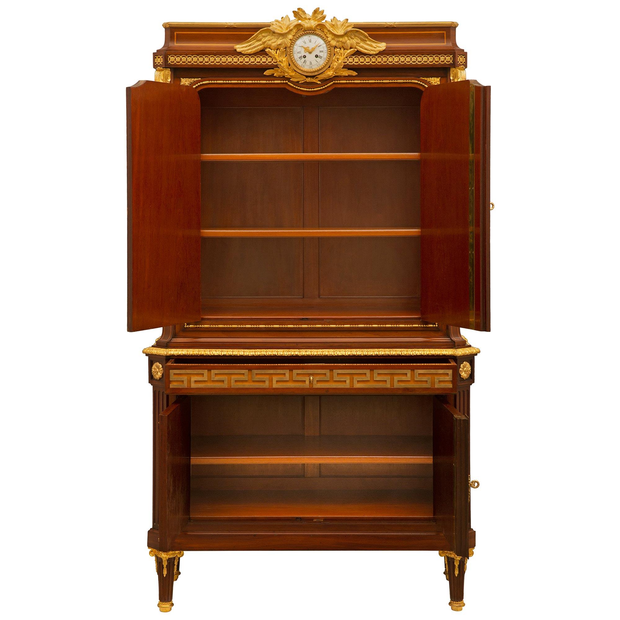 A stunning and extremely high quality French 19th century Louis XVI st. Mahogany, Tulipwood and ormolu clock cabinet signed Mercier Frères. The four door one drawer cabinet is raised by elegant circular tapered fluted legs with fine mottled and