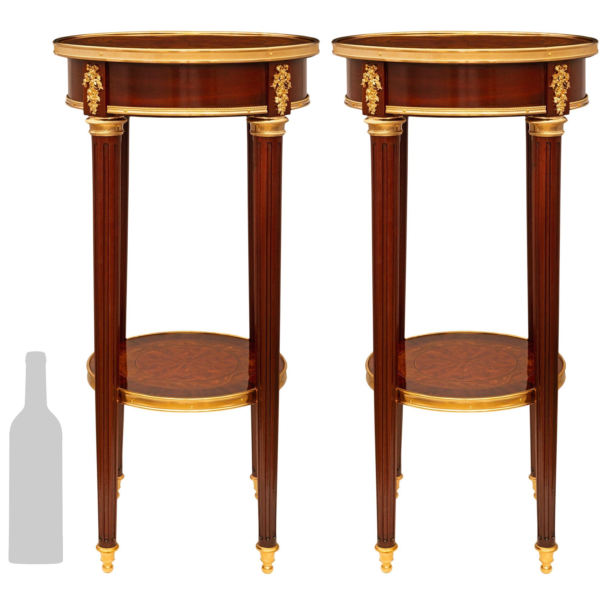 Un'elegantissima coppia di tavolini francesi del XIX secolo in mogano, tulipano, kingwood e ormolu. Ogni bellissimo tavolino si regge su quattro gambe rotonde, sottili, affusolate e scanalate, sostenute da sabot in Ormolu a forma di topie. Le