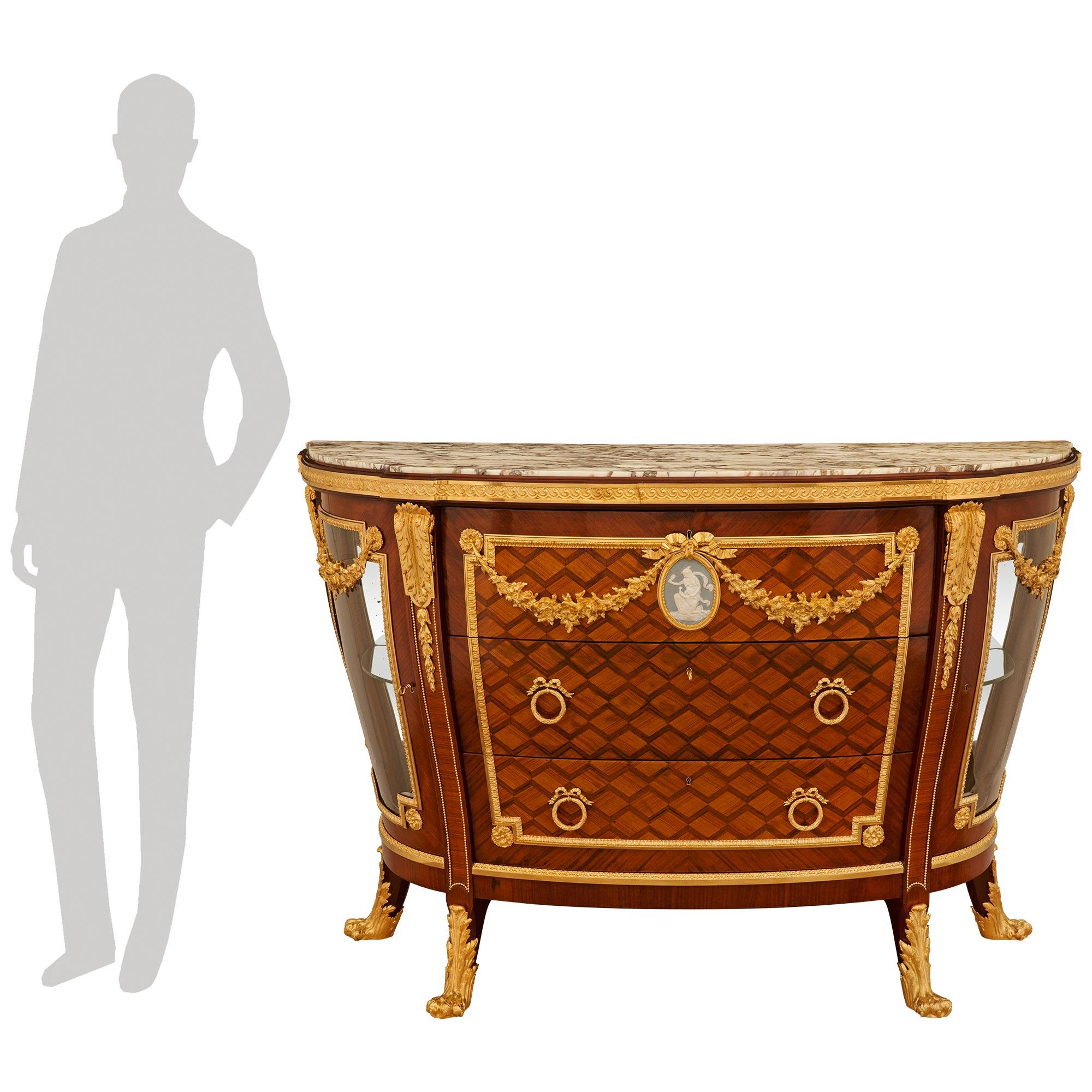 Une élégante et unique commode/vitrine en bois de tulipier, bois de roi, bronze doré, marbre et porcelaine de Wedgwood d'époque Belle Epoque. La commode repose sur quatre pieds saillants et richement décorés d'un motif de pattes rehaussé de feuilles