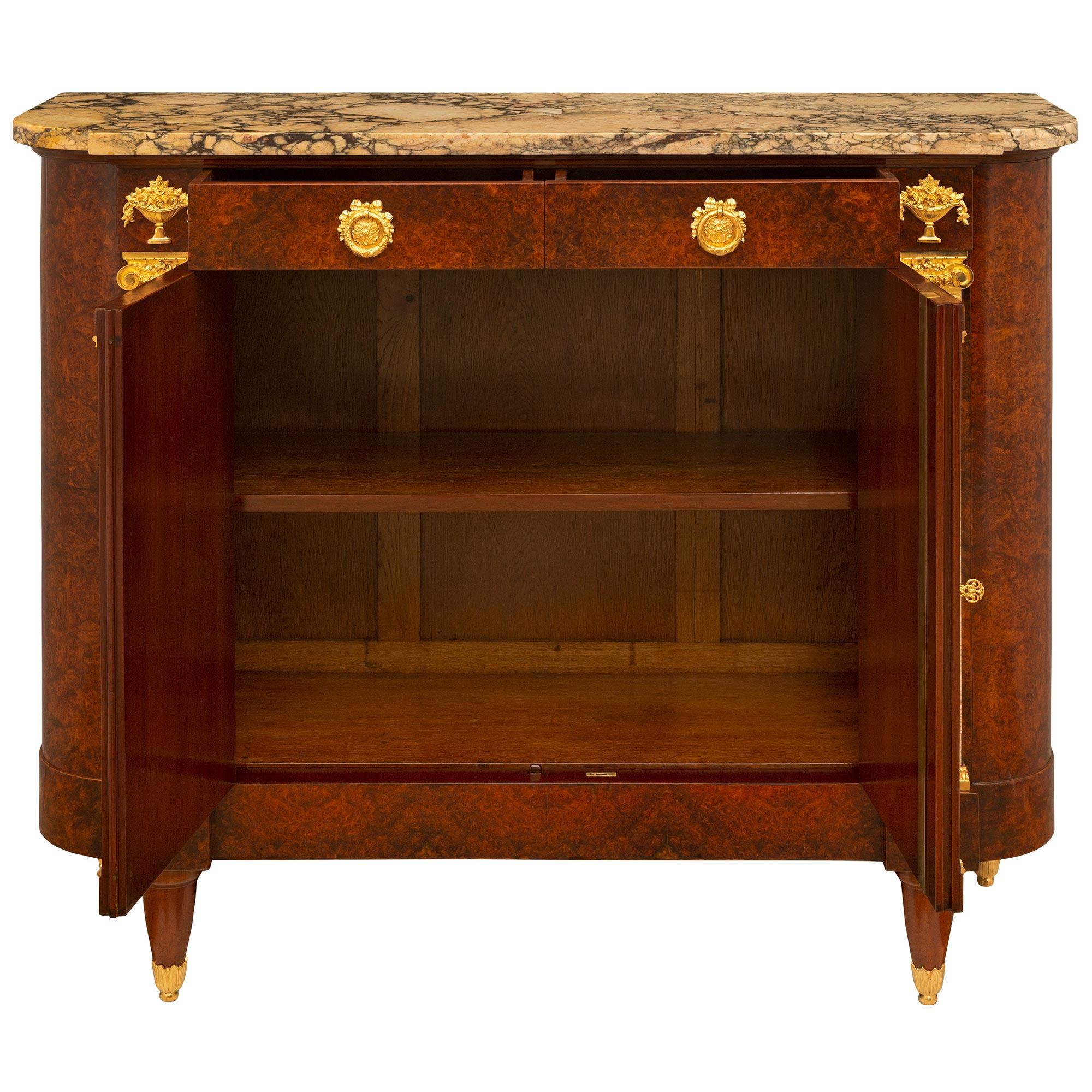 A striking French 19th century Louis XVI st. burl Walnut, ormolu, Sarrancolin and Brèche marble buffet. The two door two drawer buffet is raised by elegant stout circular fluted feet with fine foliate fitted mottled sabots below impressive and most