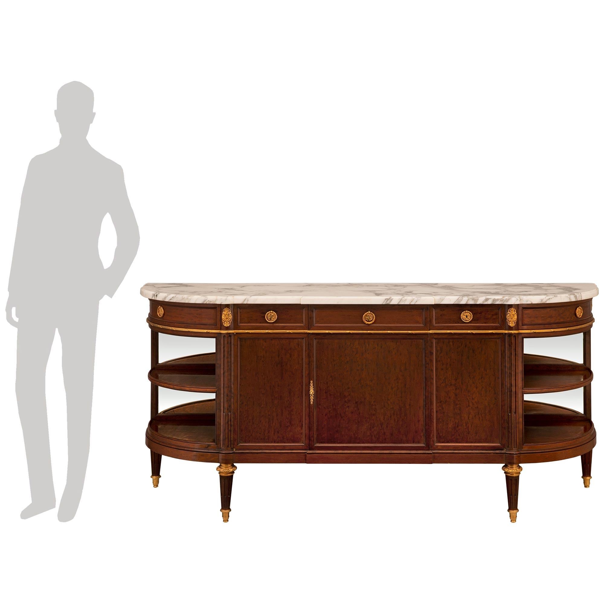 A most elegant French 19th century Louis XVI st. mouchette mahogany, ormolu and marble five drawer two door buffet. The buffet is raised by fine circular tapered fluted legs with ormolu sabots and fine decorative foliate top caps. At the center are
