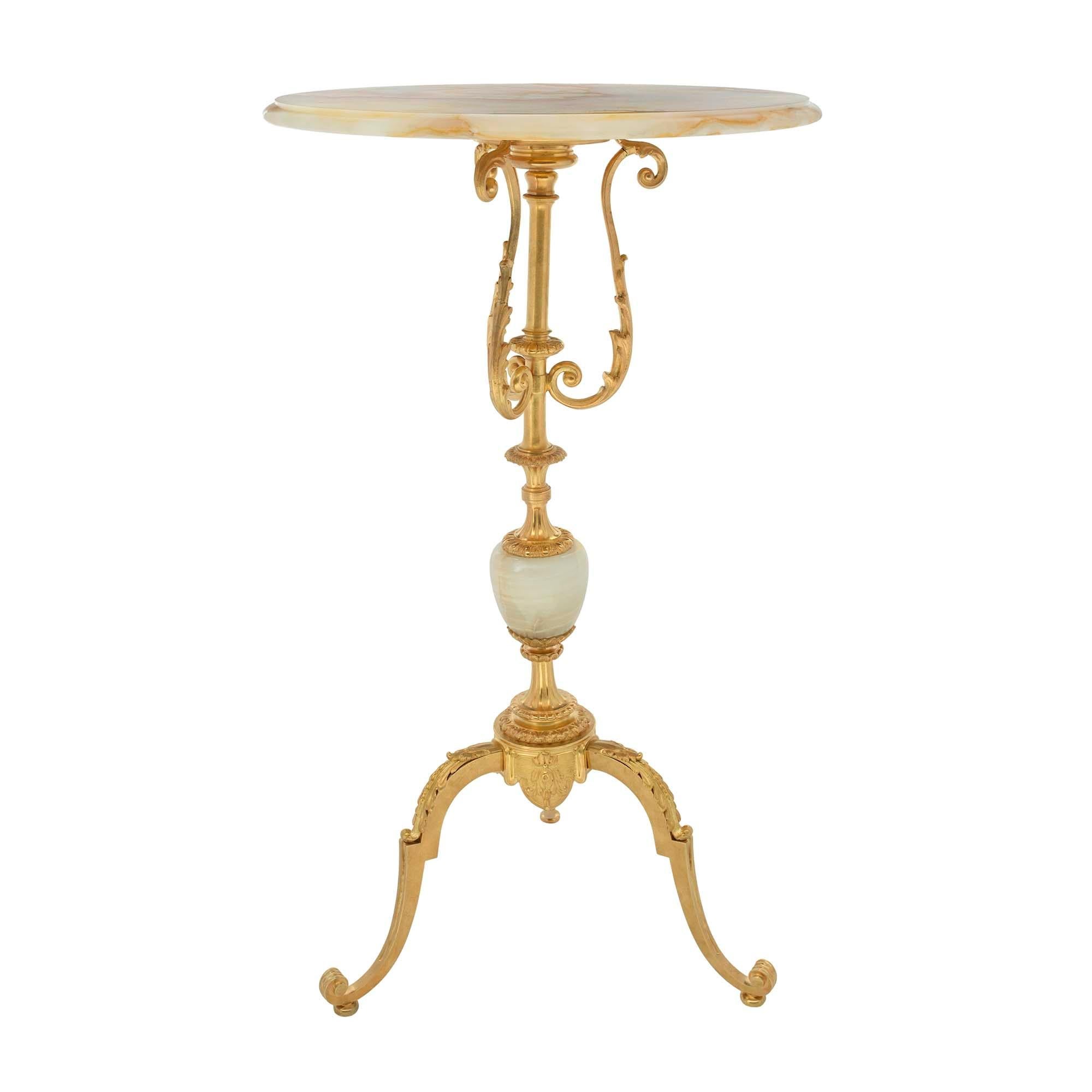 A beautiful and extremely elegant French 19th century Louis XVI st. Napoleon III period onyx and ormolu side table. The table is raised by a scrolled tripod shaped base with a lightly scrolled design and large acanthus leaves. The central support