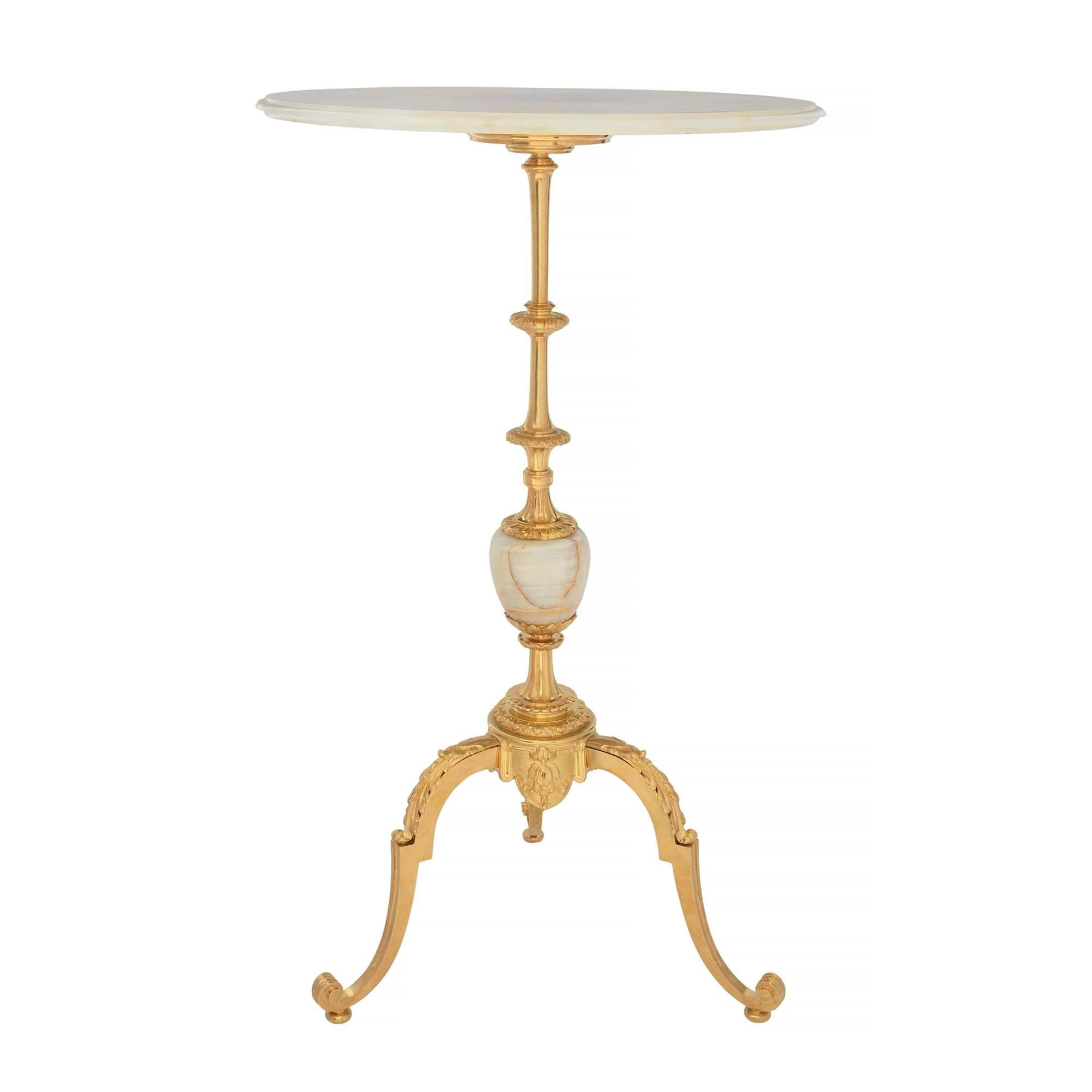 An extremely elegant French 19th century Louis XVI st. Napoleon III period onyx and ormolu side table. The table is raised by a scrolled tripod shaped base with a lightly scrolled design and large acanthus leaves. The central support displays fluted