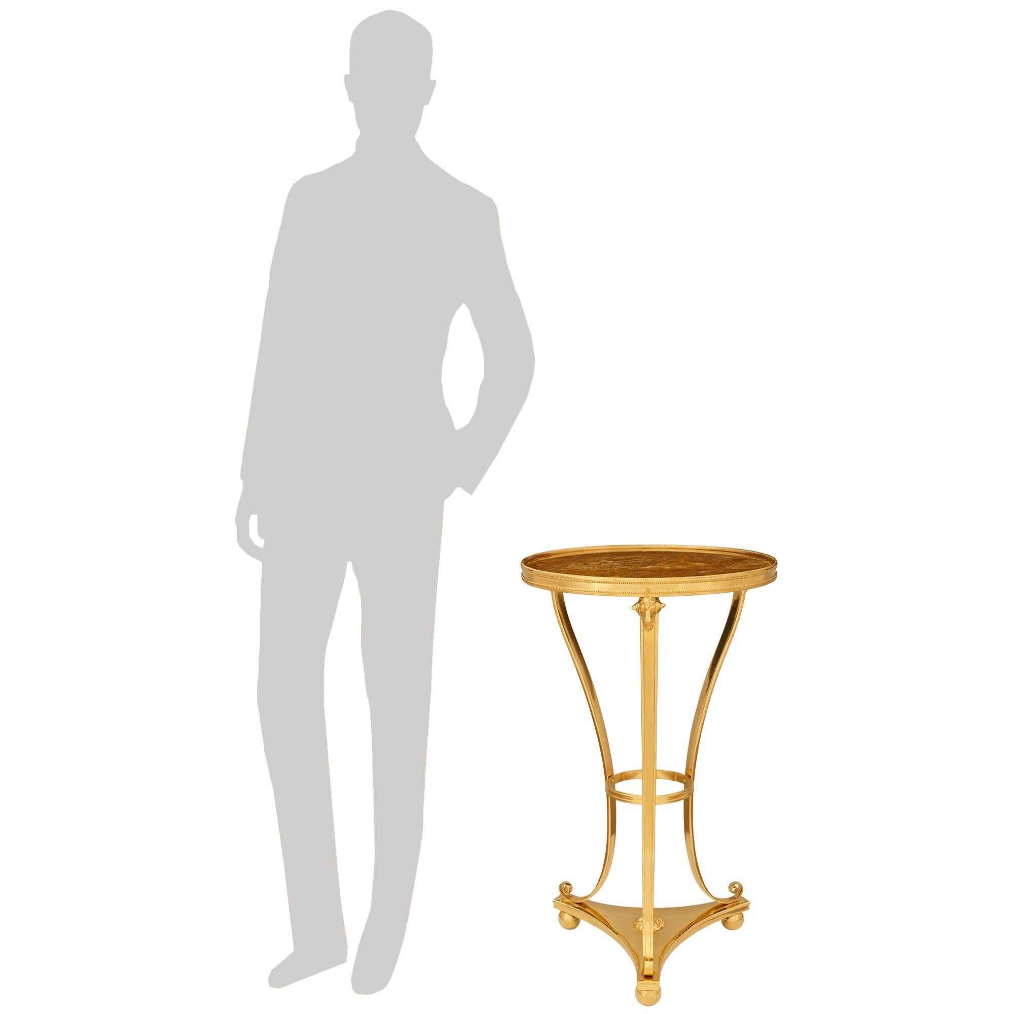 Une élégante et très décorative table d'appoint en bronze doré et albâtre de style Louis XVI du XIXe siècle. Cette superbe table repose sur un trio de pieds boules supportant un châssis triangulaire à partir duquel s'élèvent les pieds à enroulement