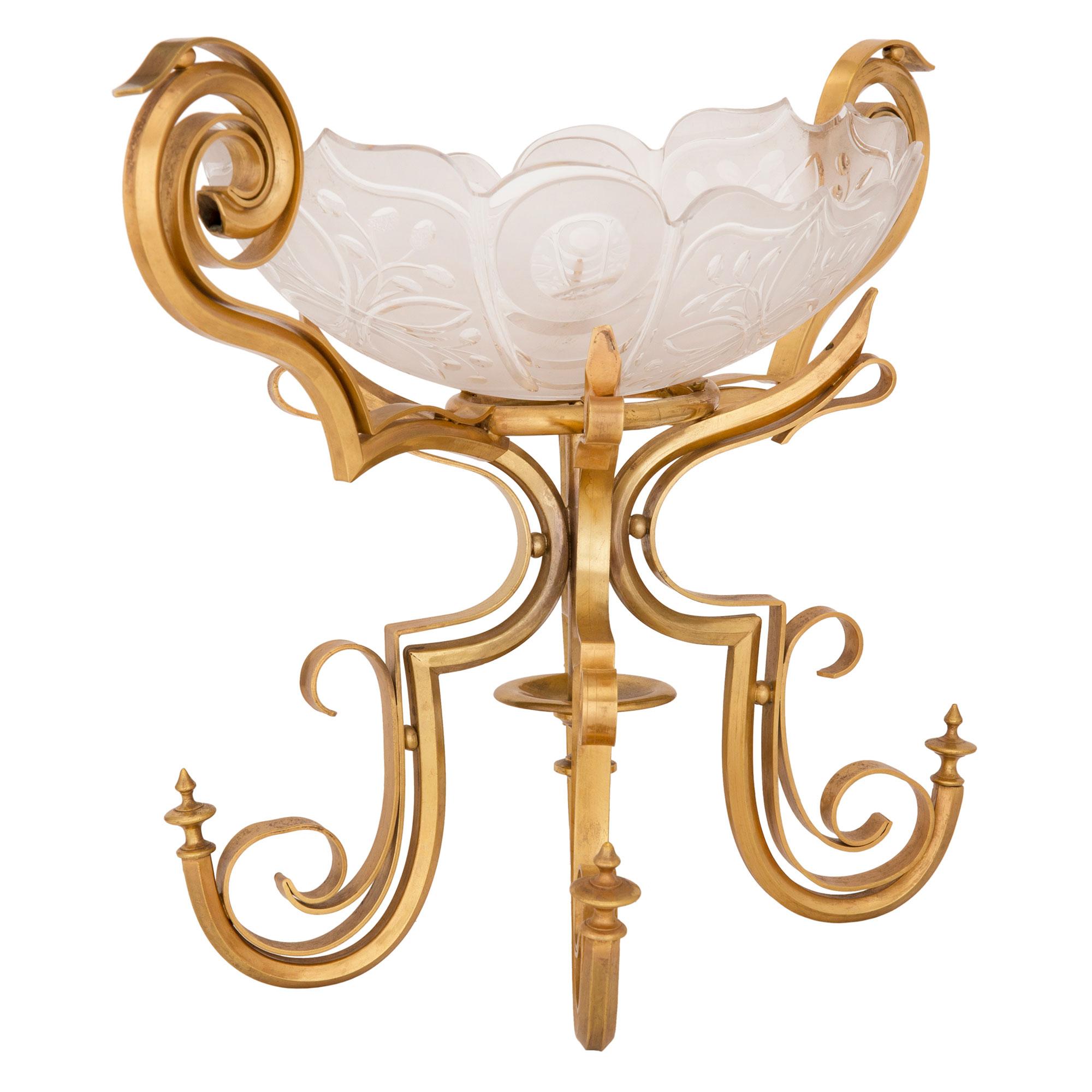 A unique and most decorative French 19th century Louis XVI st. ormolu and Baccarat crystal centerpiece bowl. The centerpiece is raised by beautiful ormolu supports with striking scrolled movements and lovely unique topies centering the central