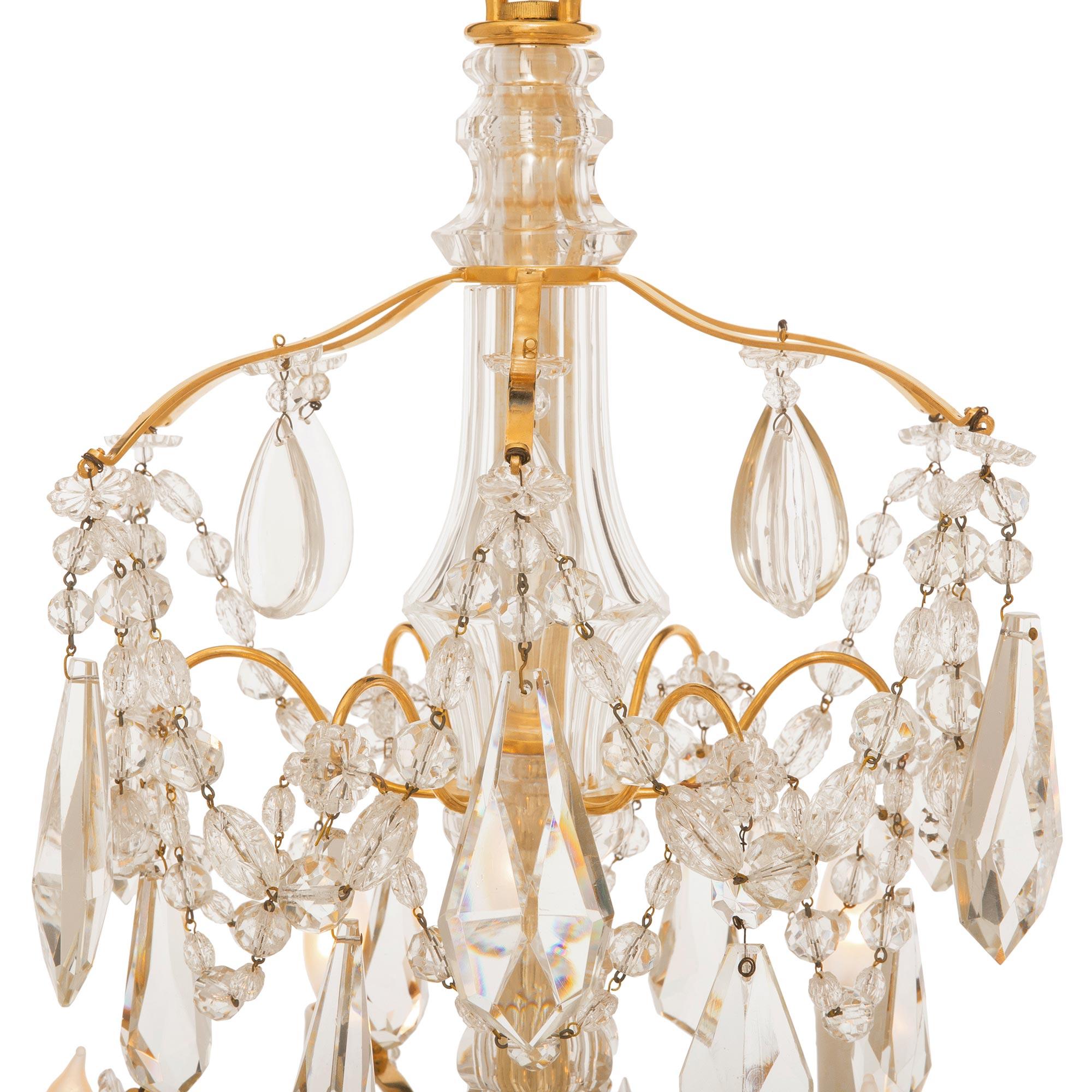 A beautiful French 19th century Louis XVI st. ormolu and Baccarat crystal chandelier. The twelve arm, fourteen light chandelier is centered by a striking facetted bottom crystal ball below a stunning array of exquisite kite and prism shaped cut