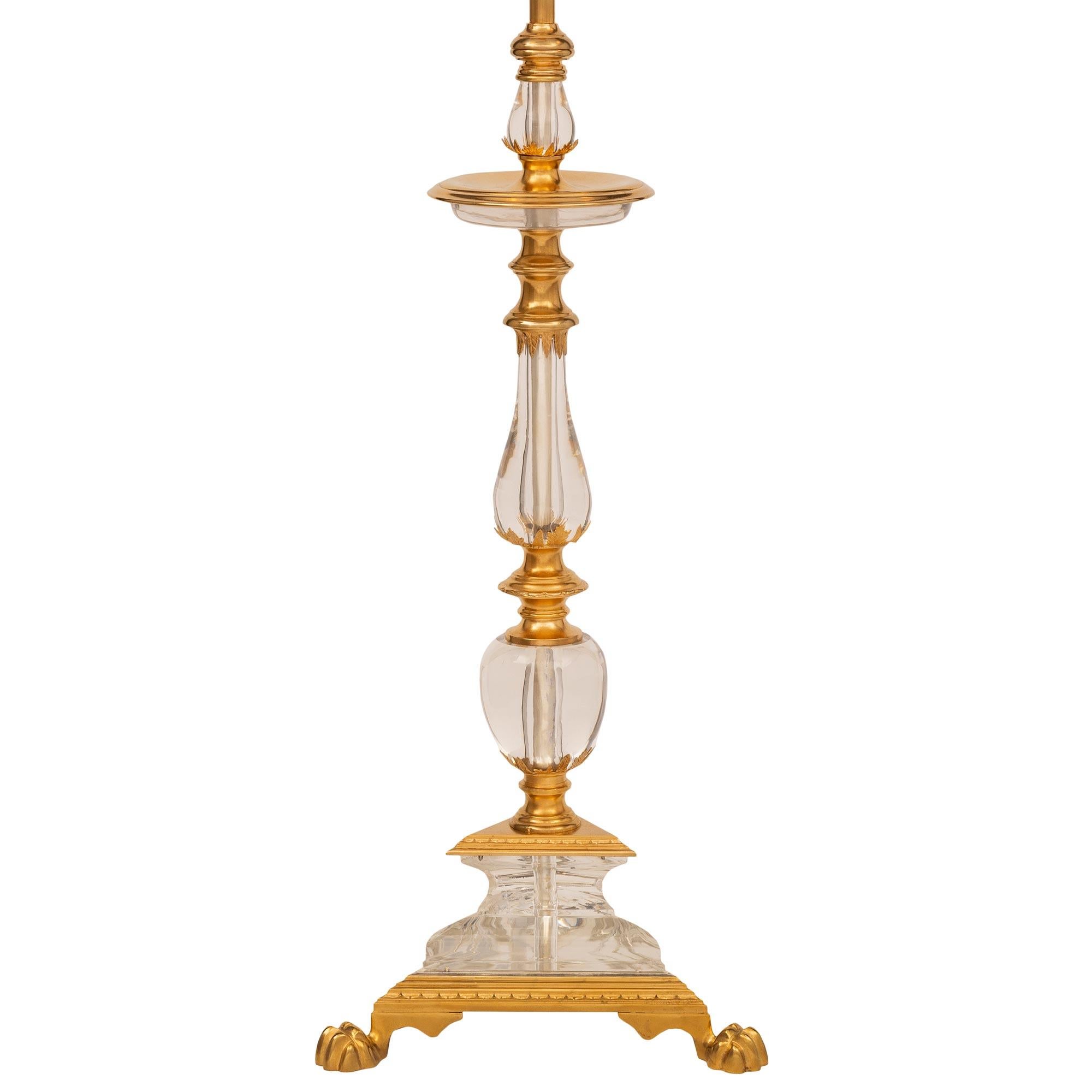 A unique and extremely elegant French 19th century Louis XVI st. ormolu and Baccarat crystal lamp. The lamp is raised by a striking and most decorative triangular base with a fine mottled wrap around ormolu band, handsome richly chased paw feet, and