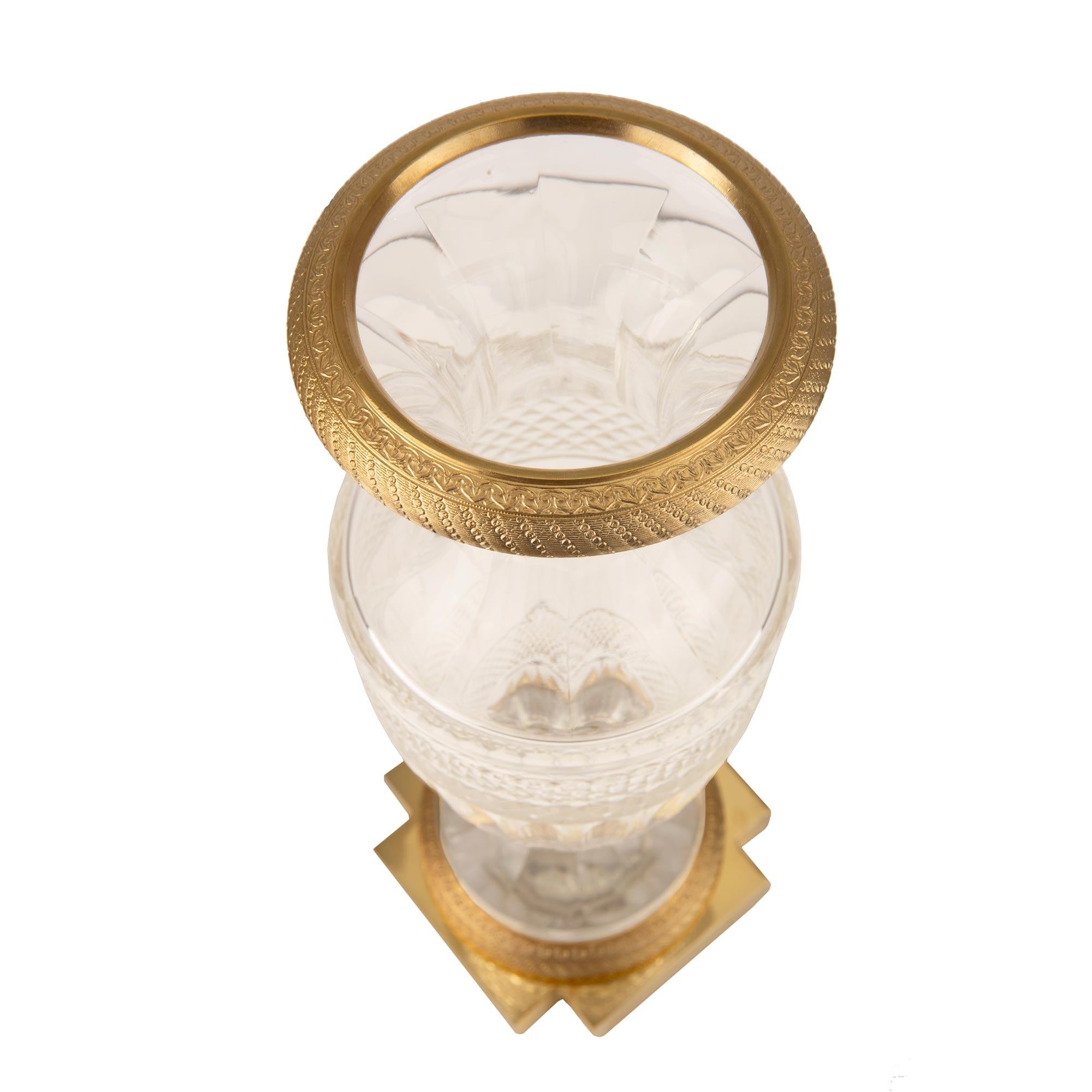 A most elegant French 19th century Louis XVI st. ormolu and Baccarat crystal vase. The vase is raised by a square base with cut corners and a beautiful richly chased wrap around ormolu band. The center of the base, under the crystal socle, is