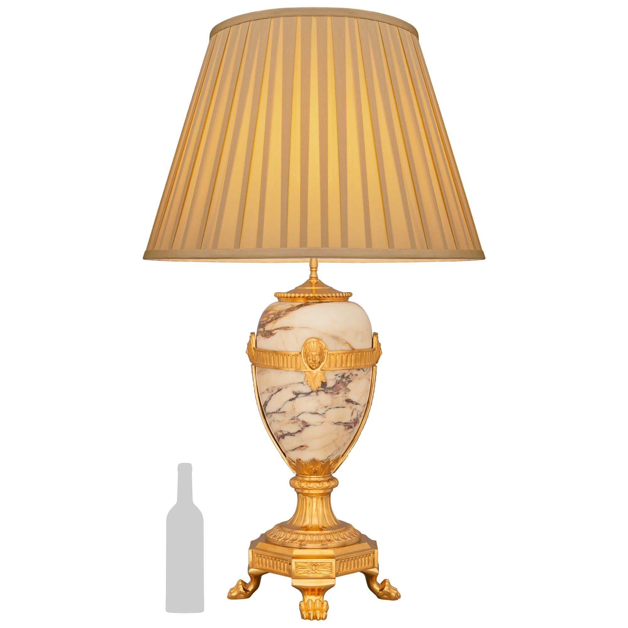 Una bella ed elegante lampada francese del XIX secolo in stile Luigi XVI in ormolu e marmo di Violette. Questa lampada che cattura l'attenzione è sollevata da una base quadrata in Ormolu con angoli tagliati e sostenuta da quattro piedi a zampa. La
