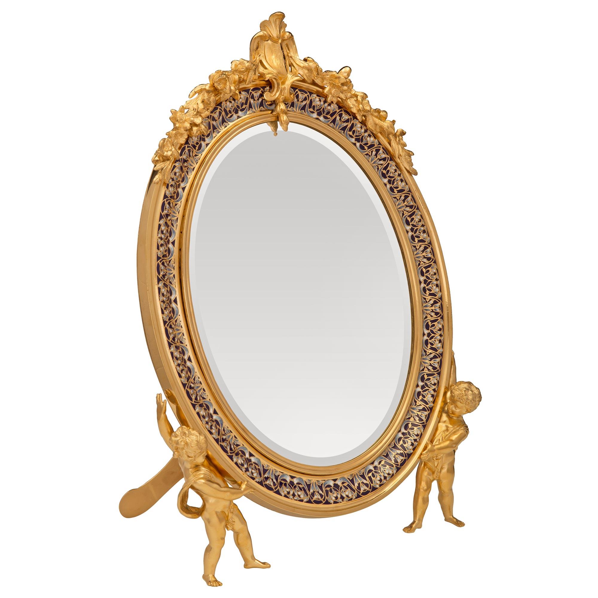 A stunning and extremely unique French 19th century Louis XVI st. ormolu and cloisonné vanity mirror signed Susse Frères Paris. The mirror retains its original mirror plate set within a sensational and extremely decorative mottled oval ormolu frame