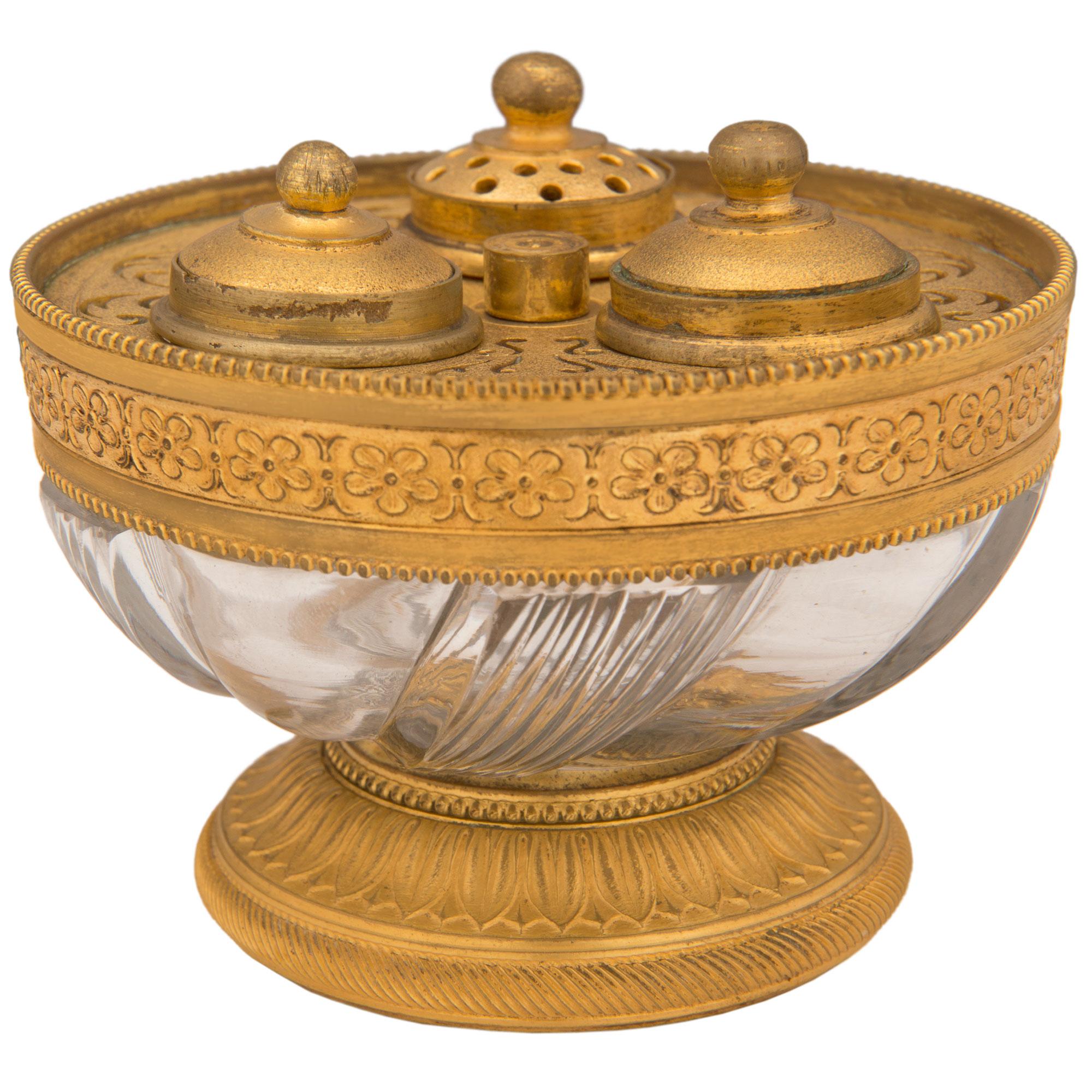 An elegant French 19th century Louis XVI st. ormolu and crystal inkwell. The inkwell is raised by a fine circular ormolu base with a lovely reeded and richly chased palmette design. Above the fine mottled base is the beautiful crystal bowl with a