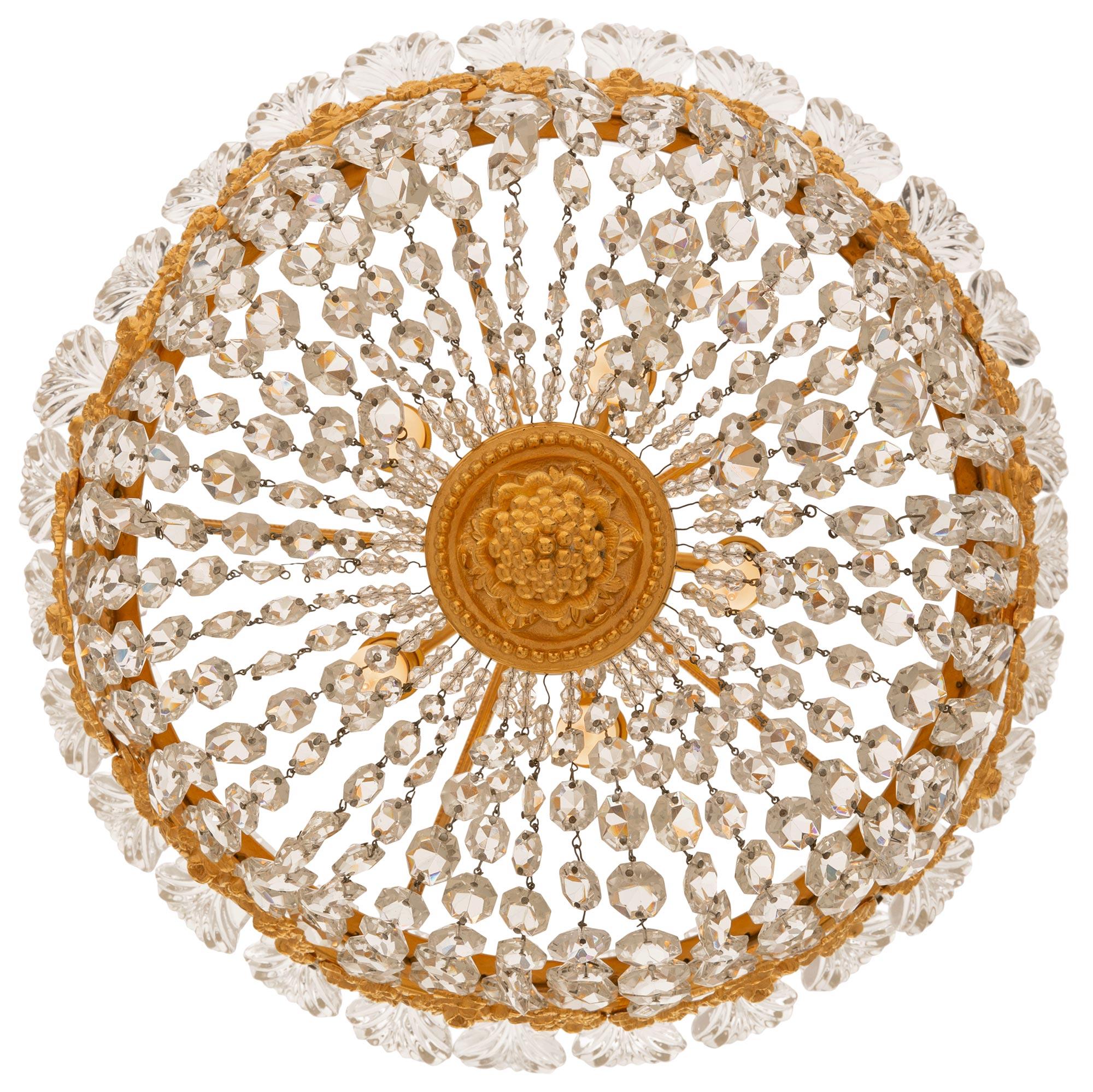 Ravissant et très élégant lustre plafonnier en bronze doré et cristal de style Louis XVI du XIXe siècle. Le plafonnier circulaire à cinq lumières est centré par un charmant fleuron à baies sous un étage en bronze doré tacheté d'où partent de