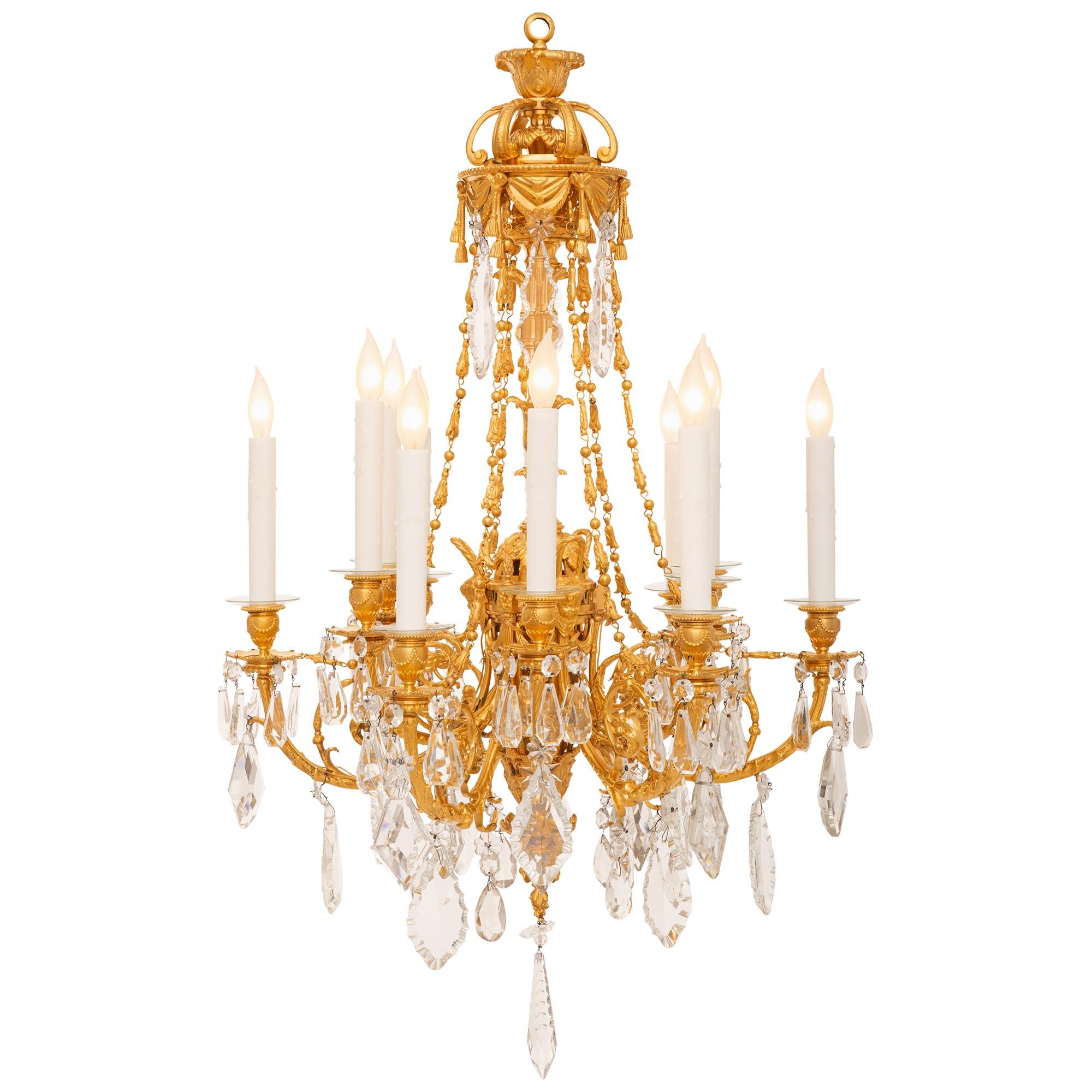 Un magnifico e pregiato lampadario francese del XIX secolo in stile Luigi XVI con ormolu e vetro tagliato. Questo lampadario a dodici bracci e dodici luci è centrato da un finalino in vetro con taglio a prisma che pende sotto una rosetta in vetro e