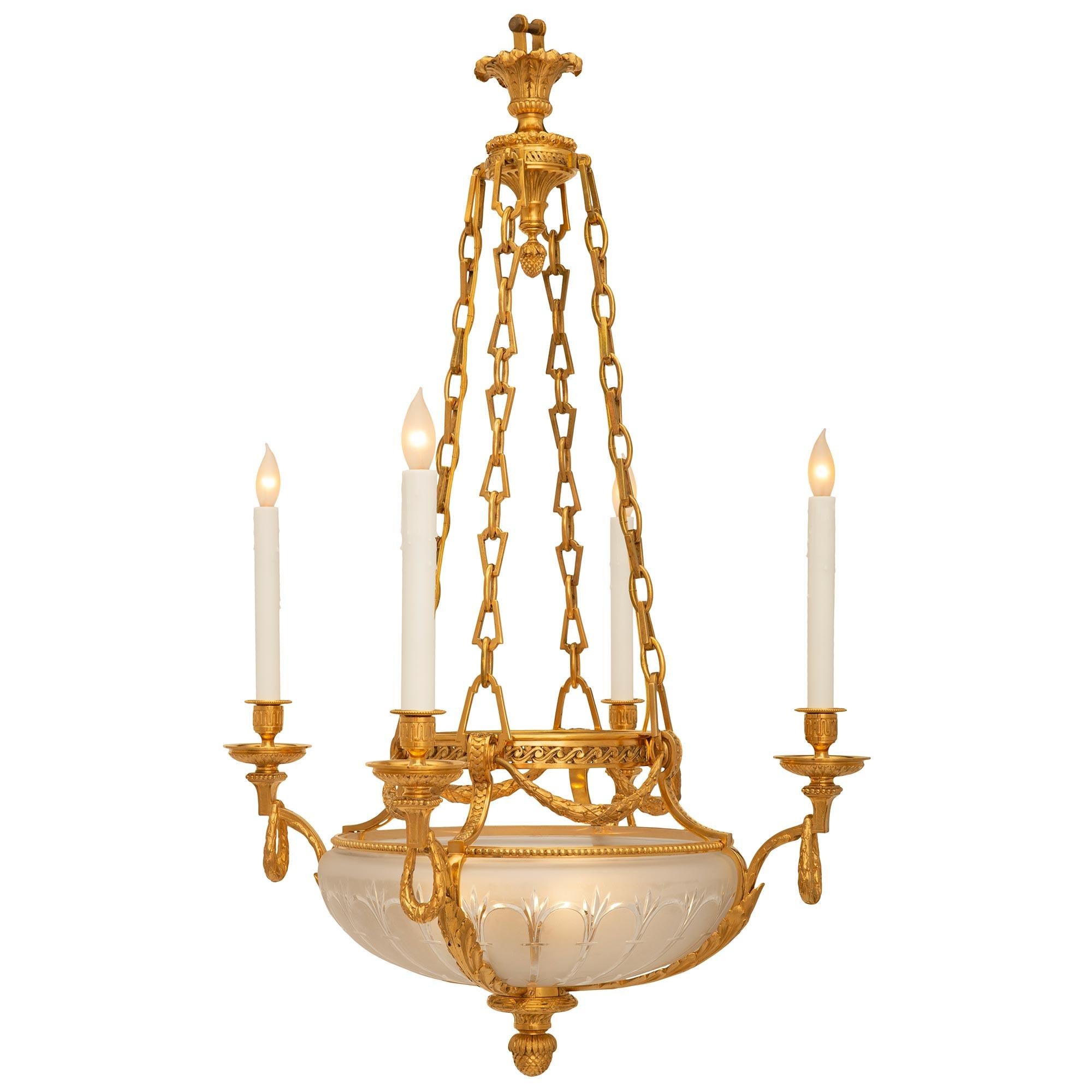 A beautiful and most unique French 19th century Louis XVI st. ormolu and etched frosted crystal chandelier. The four arm eight light chandelier is centered by a beautiful richly chased bottom acorn finial below fine spiral fluted and tied reeded