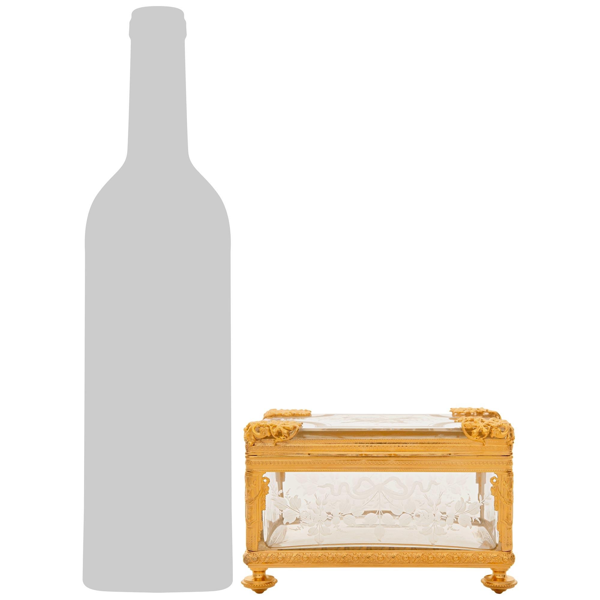 Un élégant coffret en verre et bronze doré de style Louis XVI du XIXe siècle. Cette charmante boîte repose sur quatre pieds en forme de topie, sous un bandeau de feuillage et de perles merveilleusement ciselé. Des supports en forme de colonnes