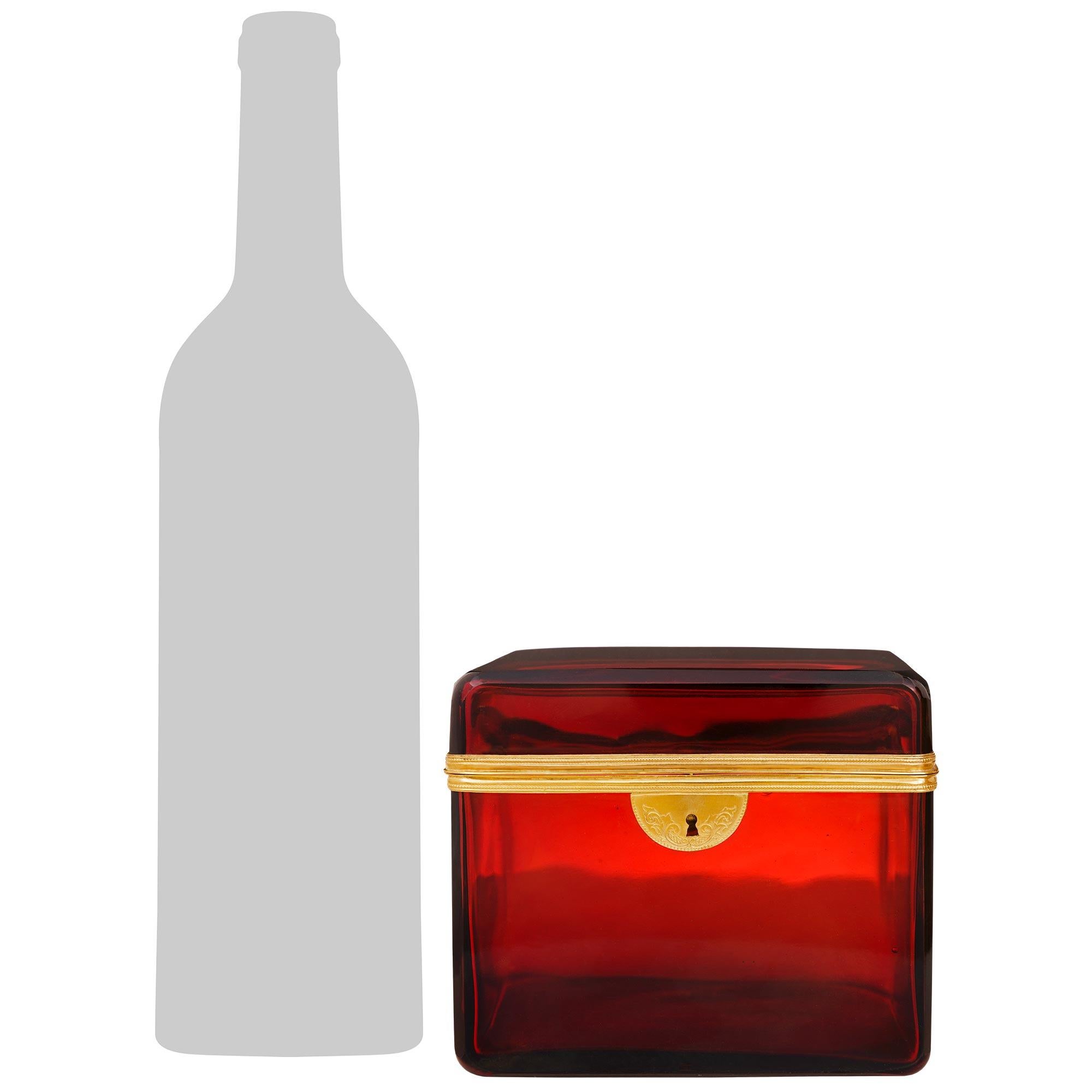 A charming and most decorative French 19th century Louis XVI st. Ormolu and Glass box. This attractive ruby red glass lidded box is raised on its hand blown glass base with rounded corners. The top and bottom rims are accented by richly chased