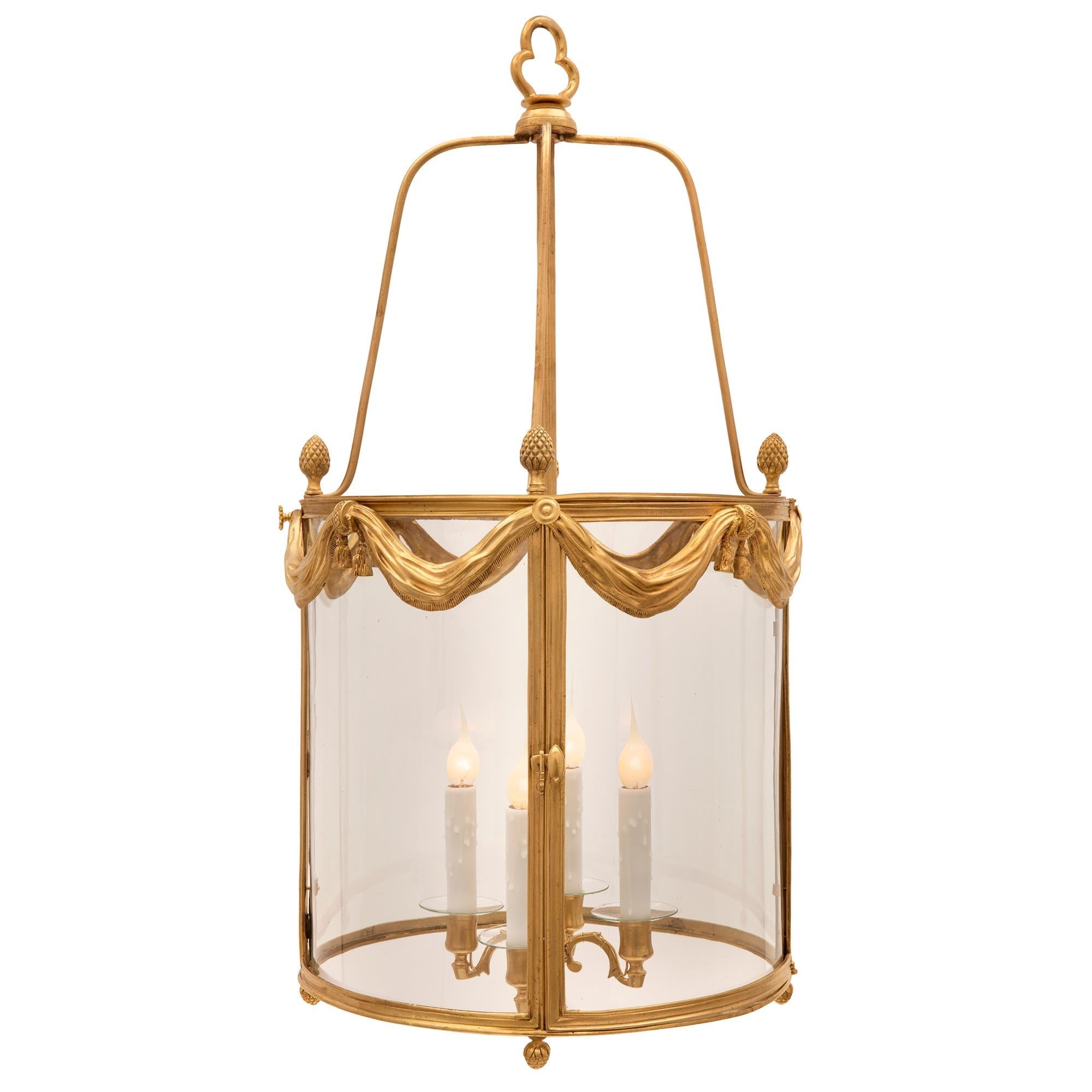 A charming and high quality French 19th century Louis XVI st. ormolu and hand blown glass lantern. The lantern displays a fine mottled bottom wrap around ormolu band with four lovely acorn finals. The four original curved hand blown glass panes are