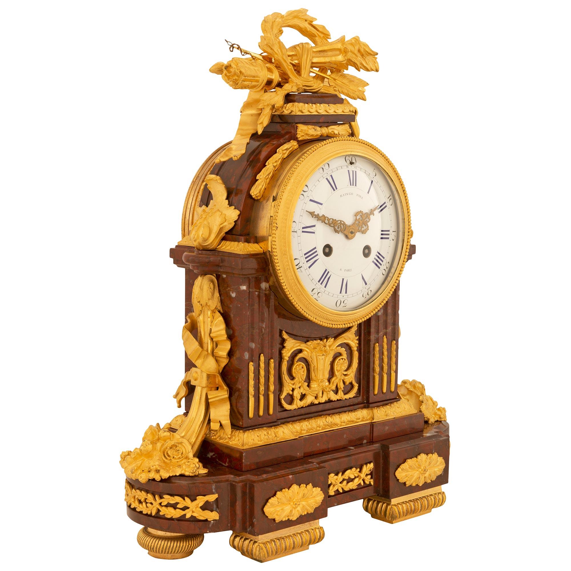 Une étonnante et très haute qualité de pendule en bronze doré et marbre Rouge Griotte de style Louis XVI du 19ème siècle, signée Raingo Frères. L'horloge est soutenue par deux élégants supports rectangulaires à cannelures à l'avant et par des pieds
