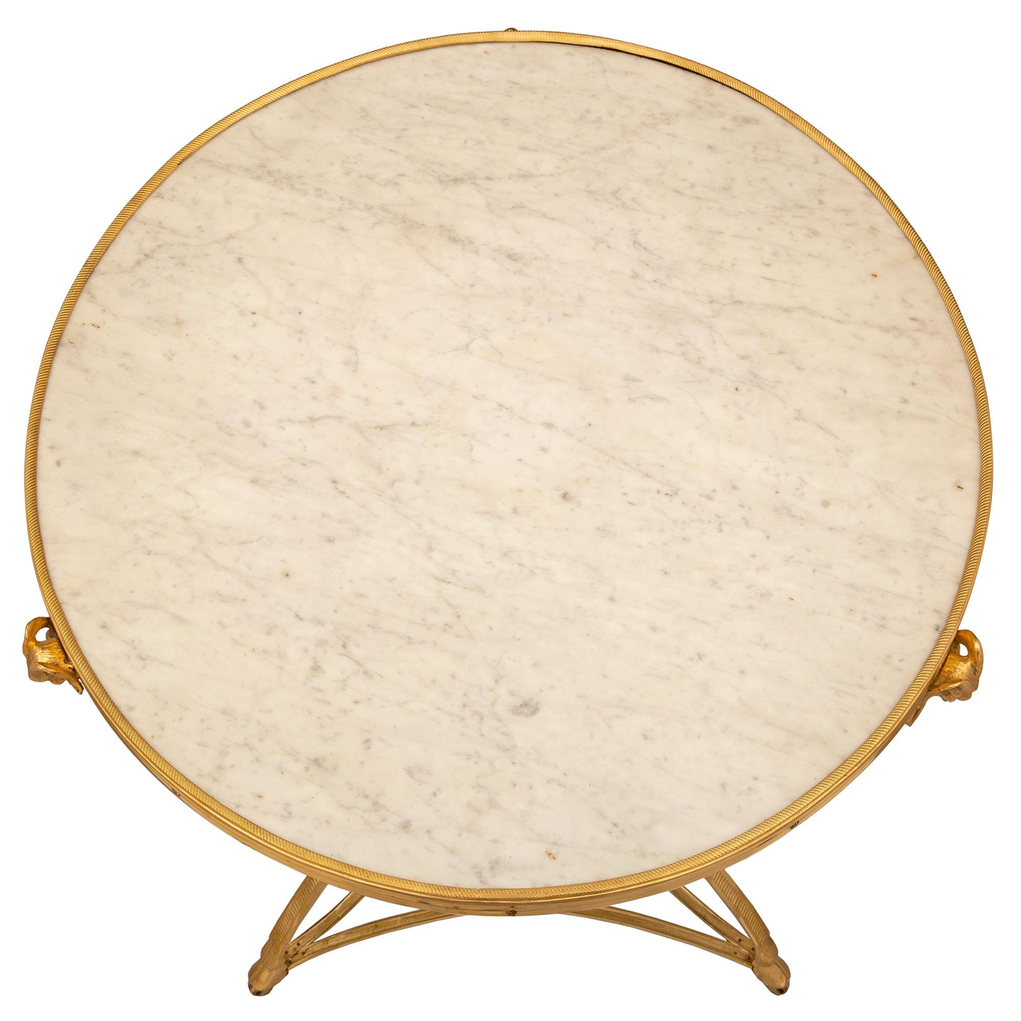 Magnifique table d'appoint de style Louis XVI du XIXe siècle en bronze doré et marbre blanc de Carrare. La table circulaire à deux niveaux est montée sur ses roulettes d'origine, sous d'élégants pieds en sabot reliés par un châssis percé très