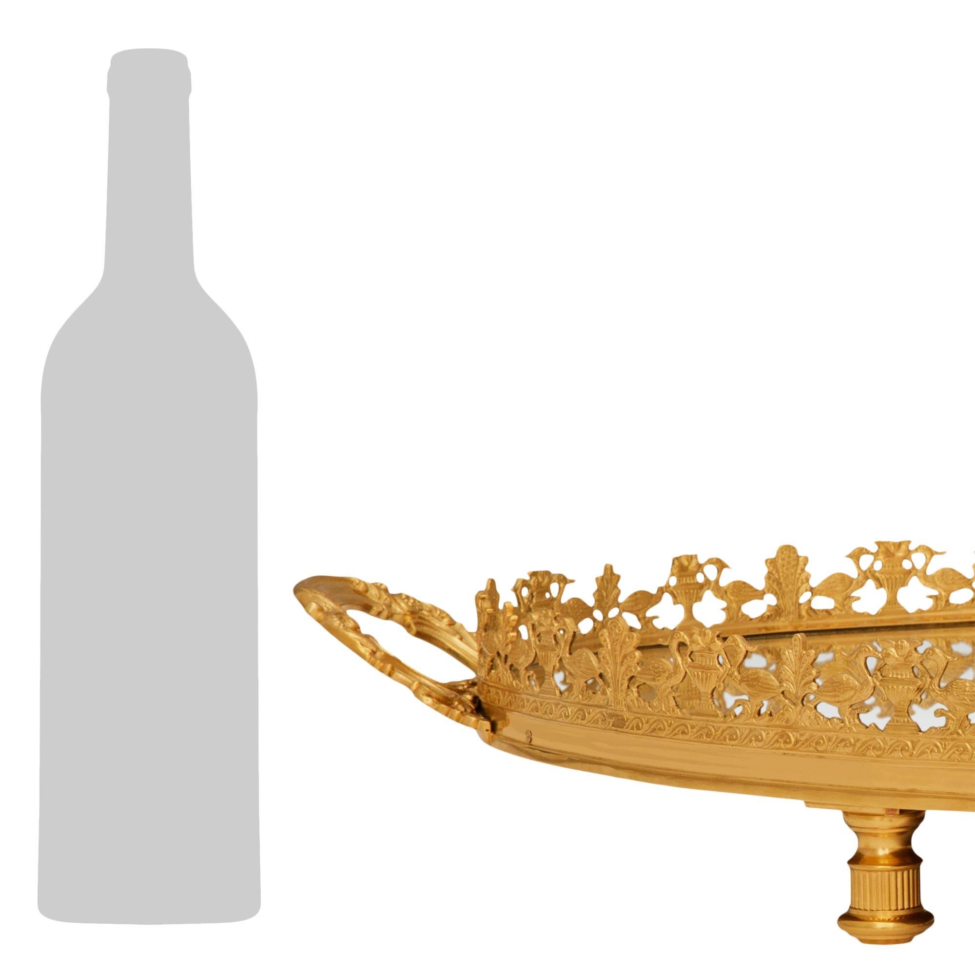 Un élégant et grand centre de table en bronze doré et miroir de style Louis XVI du 19ème siècle. Ce ravissant plateau de service est surélevé par quatre pieds cannelés en bronze doré qui soutiennent la plaque de service encadrée de miroirs. La