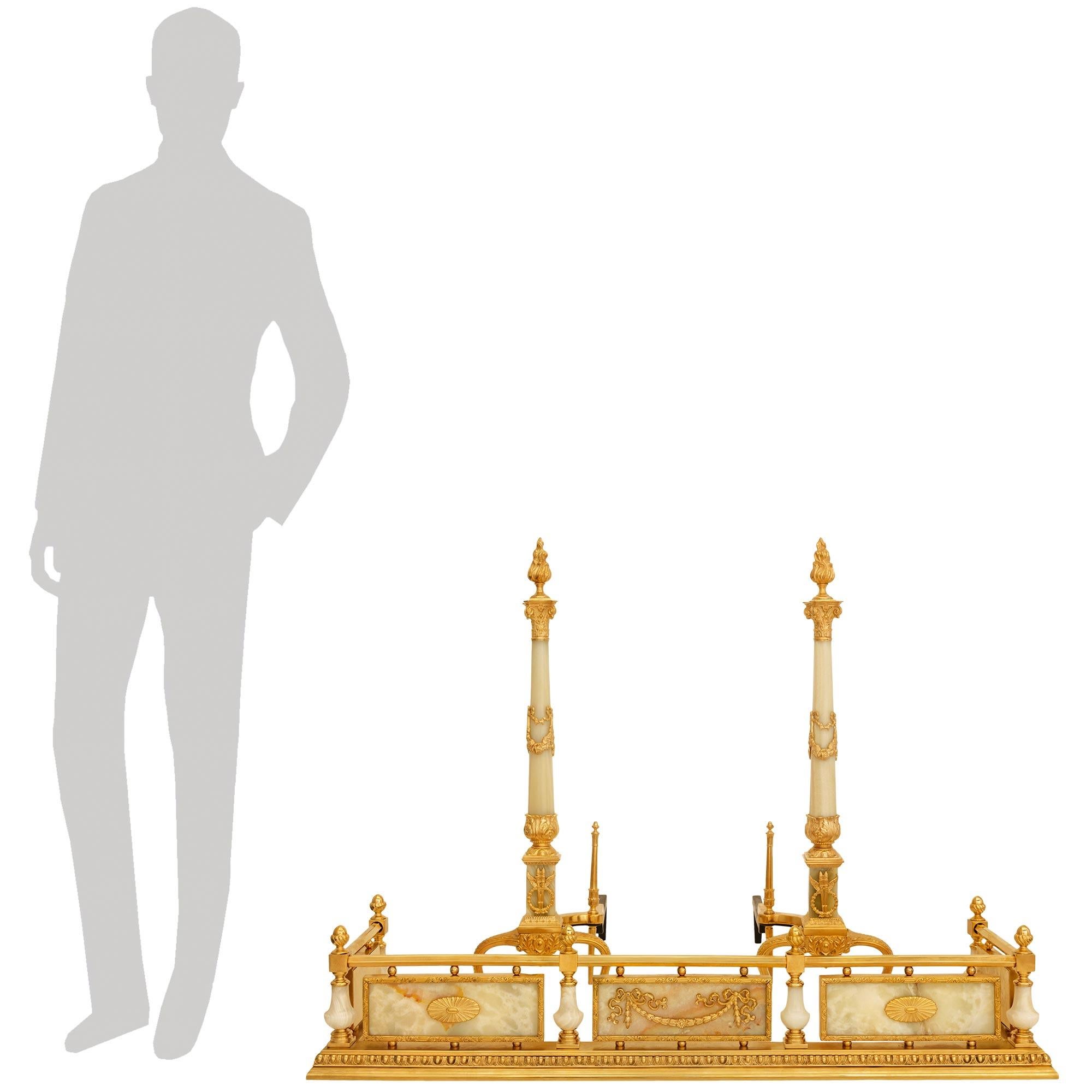 Uno splendido ed elegante set di androni e parafuoco in ormolu e onice del XIX secolo Luigi XVI. Ogni splendido ferro da stiro è sollevato da due gambe anteriori a volute in Ormolu con foglie d'acanto affusolate in alto e terminanti con piedi a