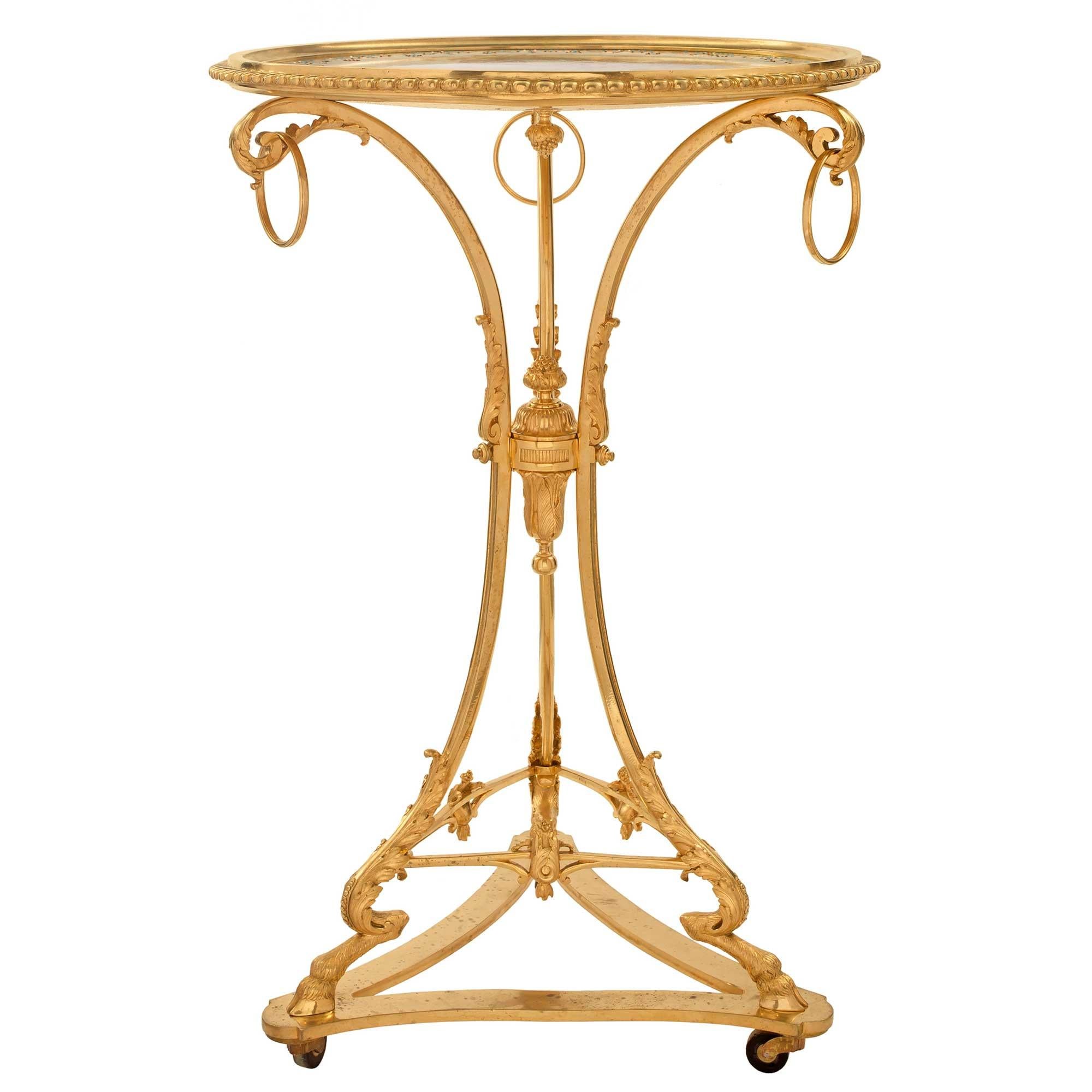 A most decorative French 19th century Louis XVI St. ormolu and porcelain Guéridon. The side table is raised by a triangular base with concave sides and its original casters. The three elegant lightly curved legs display richly chased hoof feet with