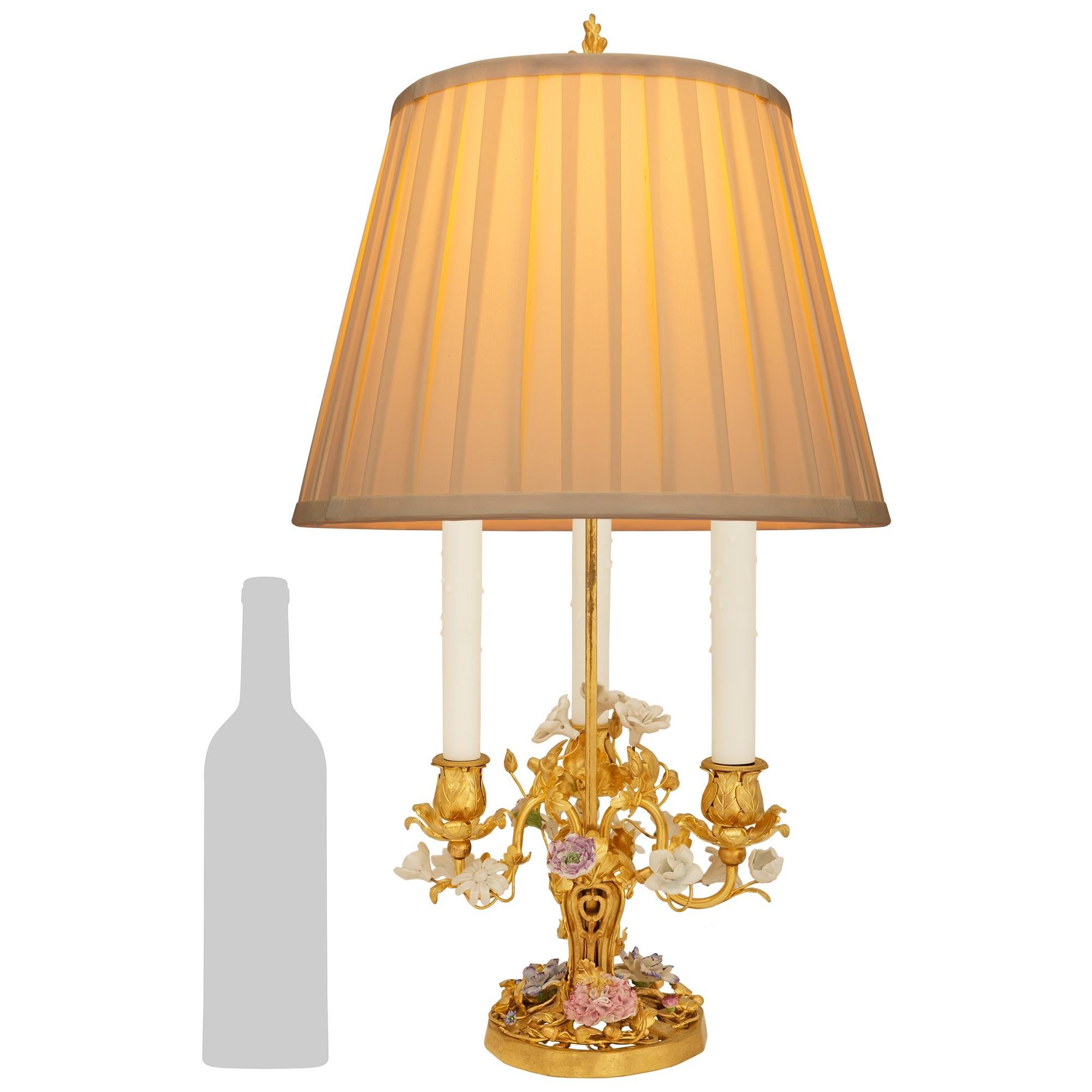 A charming and most decorative French 19th century Louis XVI st. Ormolu and Saxe Porcelain Bouillotte lamp. This elegant lamp is raised on a circular pierced Ormolu base adorned with an abundance of scrolled branches, acorns, leaves and pastel
