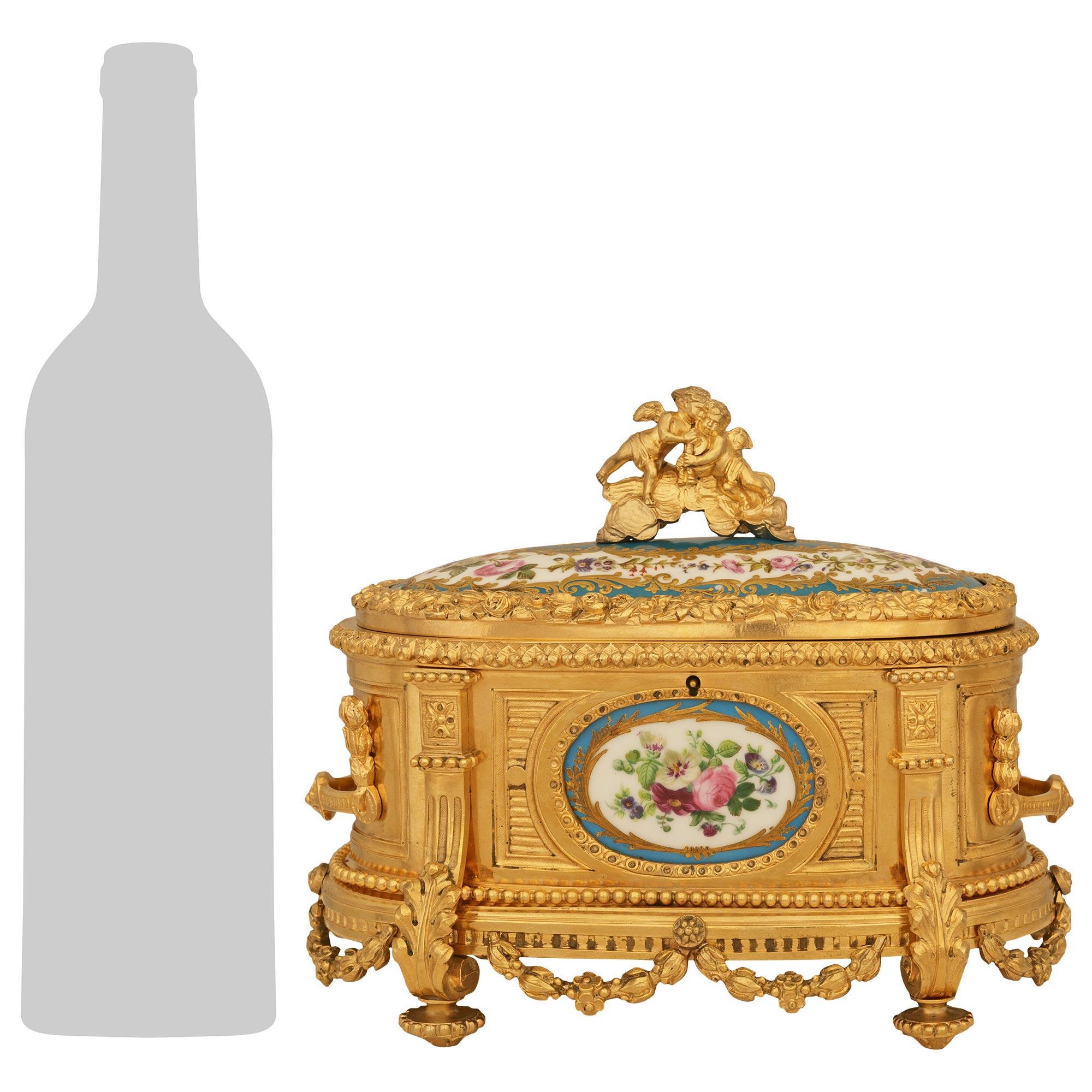 Un elegante ed elaborato cofanetto in porcellana di Sévres e Ormolu del XIX secolo. Questa graziosa scatola con coperchio ovale oblungo è sollevata da quattro piedini a forma di toupie sotto foglie d'acanto a forma di 'S'. Le gambe sono