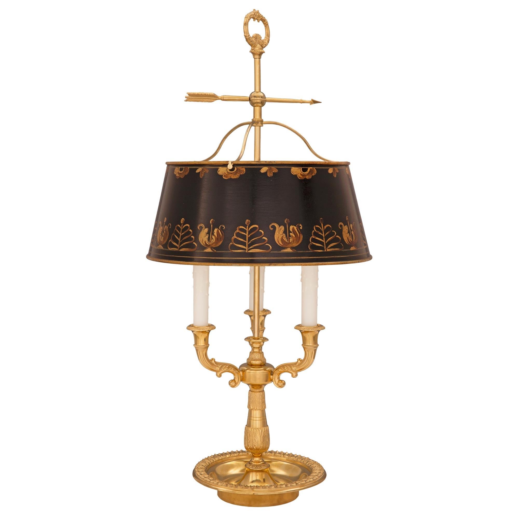 An elegant French 19th century Louis XVI st. ormolu and tole Bouillotte lamp. The charming lamp is raised by a circular bowl shaped base with a lovely wrap around foliate band. The circular central support displays an elegantly tapered design with