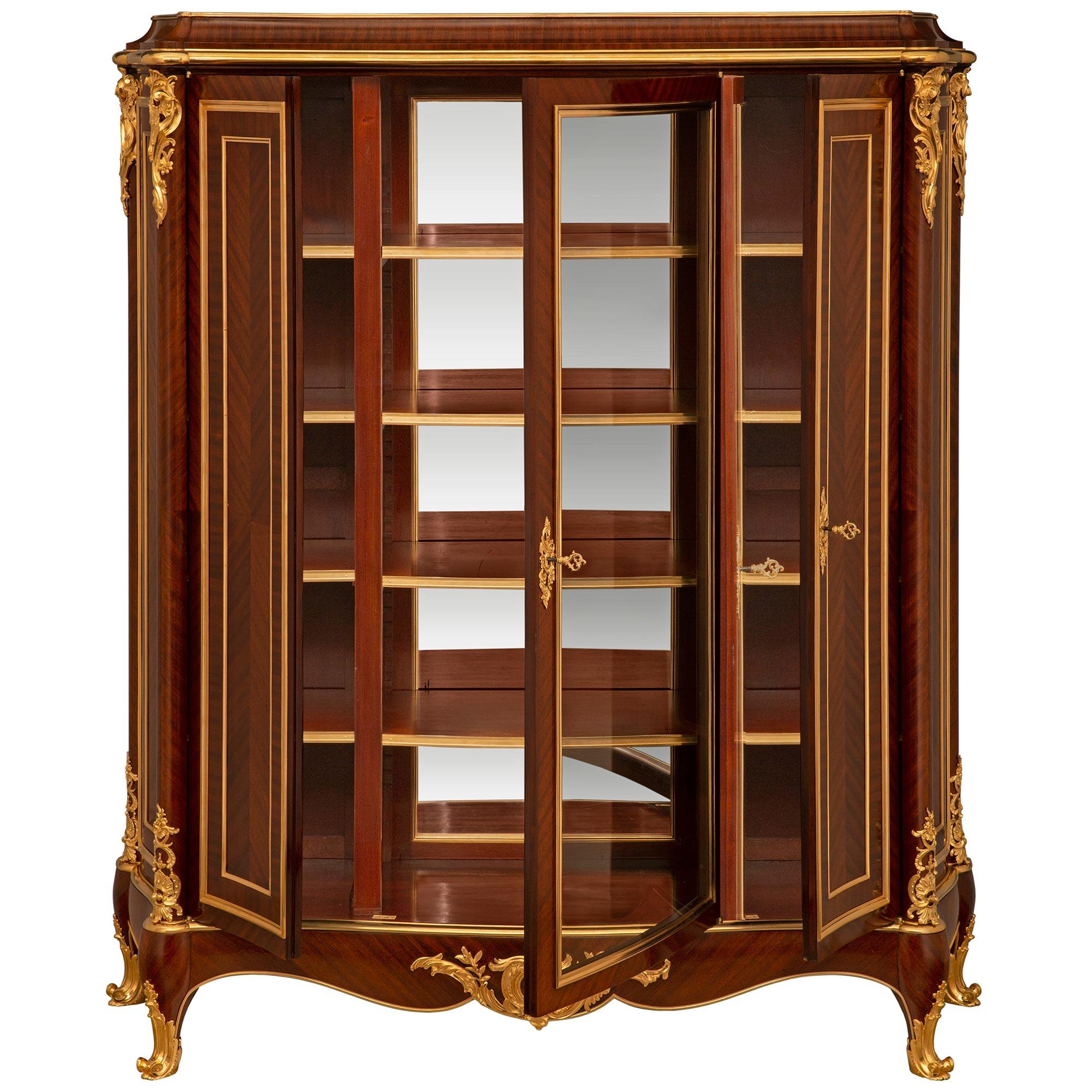 A stunning and high quality French 19th century Louis XVI st. Ormolu and Tulipwood cabinet/vitrine, signed Henry Dasson 1886. This beautiful tall rectangular three door vitrine is supported by four Tulipwood cabriole legs and wrap around Ormolu