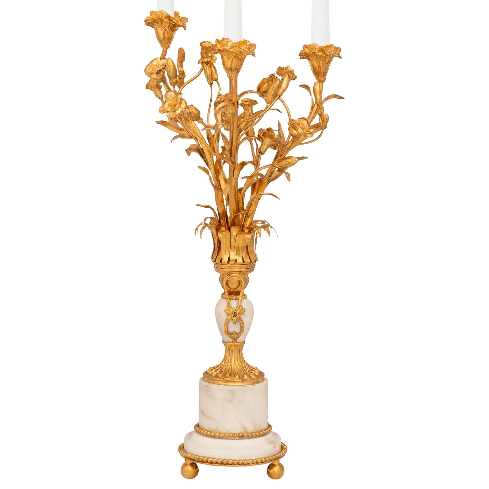 A stunning and high quality French 19th century Louis XVI st. Ormolu and white Carrara marble candelabra lamps. Each striking candelabra is supported by three ball feet below an Ormolu base plate which holds a white Carrara marble cylindrical